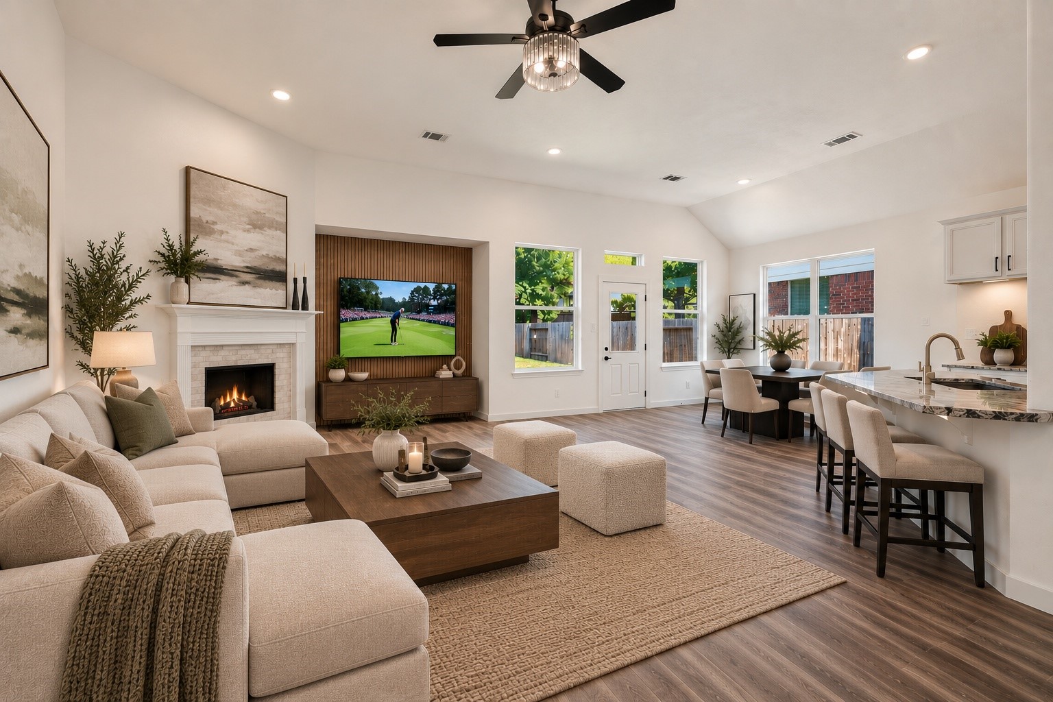 (VIRTUALLY STAGED PHOTO) See your vision come to life in this stunning family room at 18 Griffin Hill Court. Virtual staging illustrates how beautifully the space accommodates a full living set, with a cozy sofa and coffee table arranged around the fireplace, a ceiling-mounted TV, and a ceiling fan overhead  the ultimate space to relax.