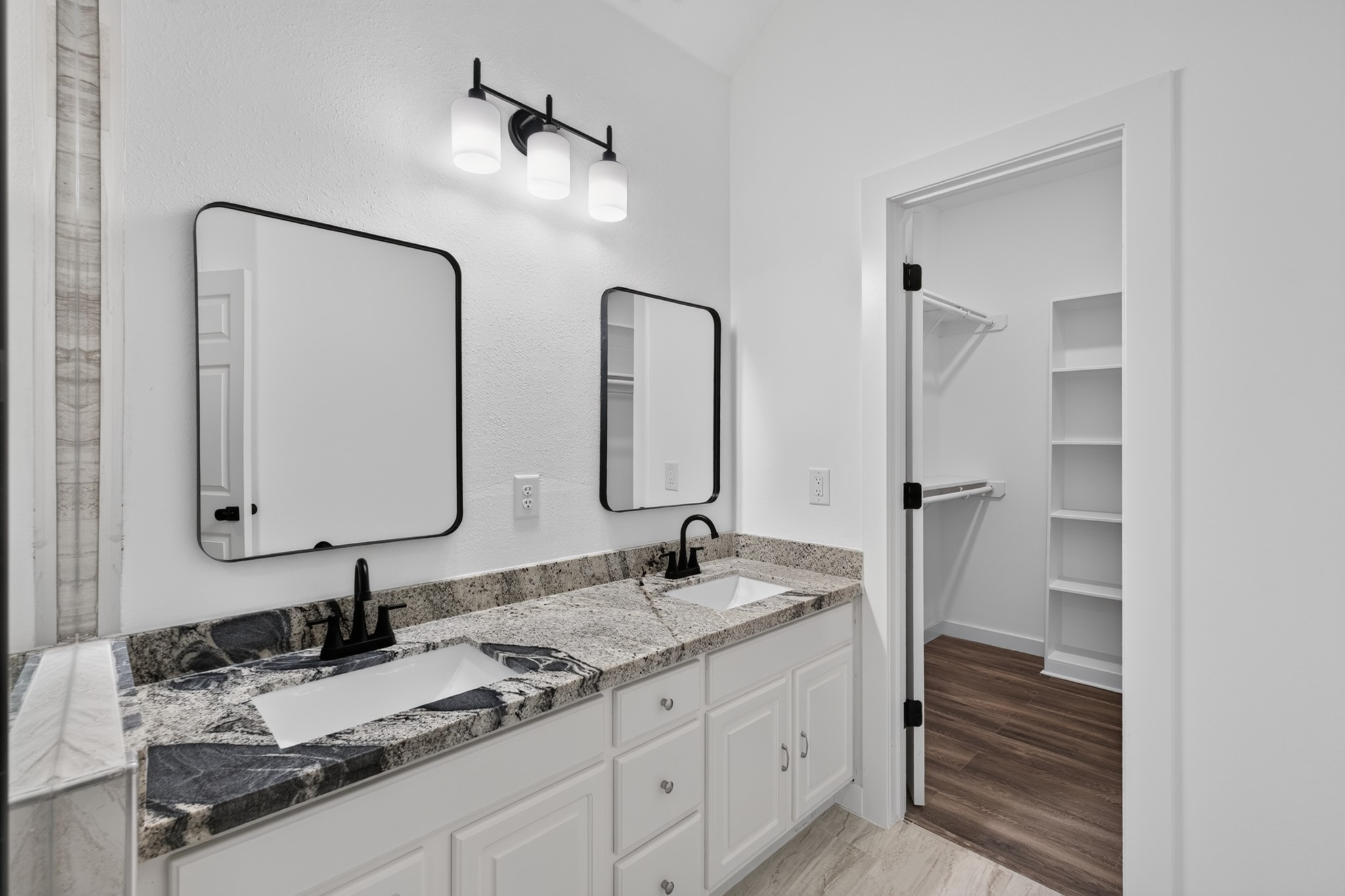 The primary bathroom at 18 Griffin Hill Court is appointed with a stunning double-sink vanity, framed mirrors, stylish modern fixtures, and beautiful tile flooring. Thoughtfully designed with ample counter space and excellent storage, this bathroom provides the comfort and functionality of a luxury retreat right within the privacy of your own home.