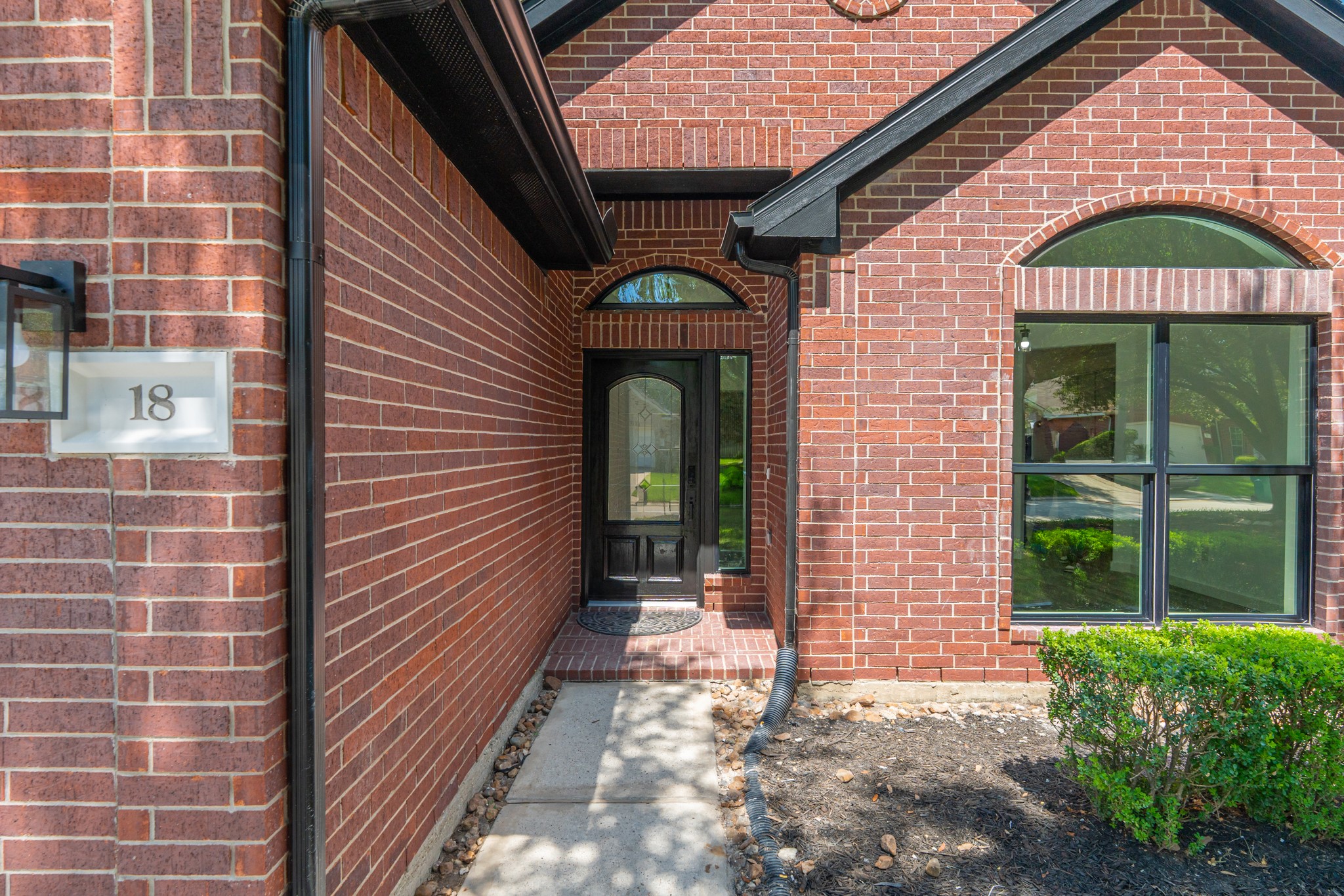 Step into elegance at the arched brick entry of 18 Griffin Hill Court. This beautifully detailed front entrance features warm red brick surrounds, a striking arched transom window above the door, and tasteful exterior lighting  setting the tone for the quality craftsmanship and attention to detail found throughout this exceptional home.