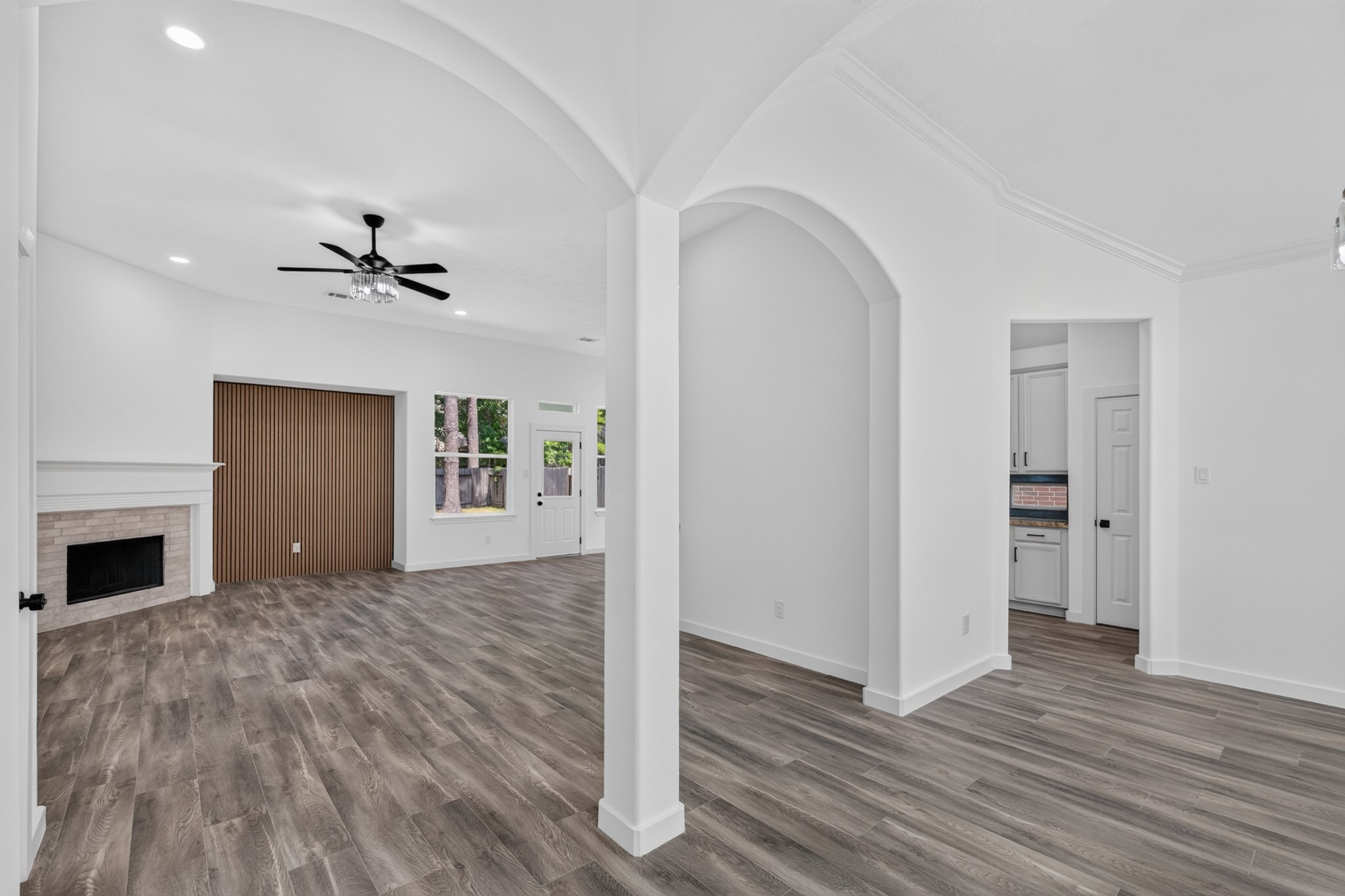 The spacious family living area at 18 Griffin Hill Court is defined by stunning architectural details including elegant arched doorway columns, soaring ceilings, and a striking fireplace. Dark hardwood-style floors flow throughout, while abundant natural light fills the open space  the perfect setting for everyday living and entertaining guests.