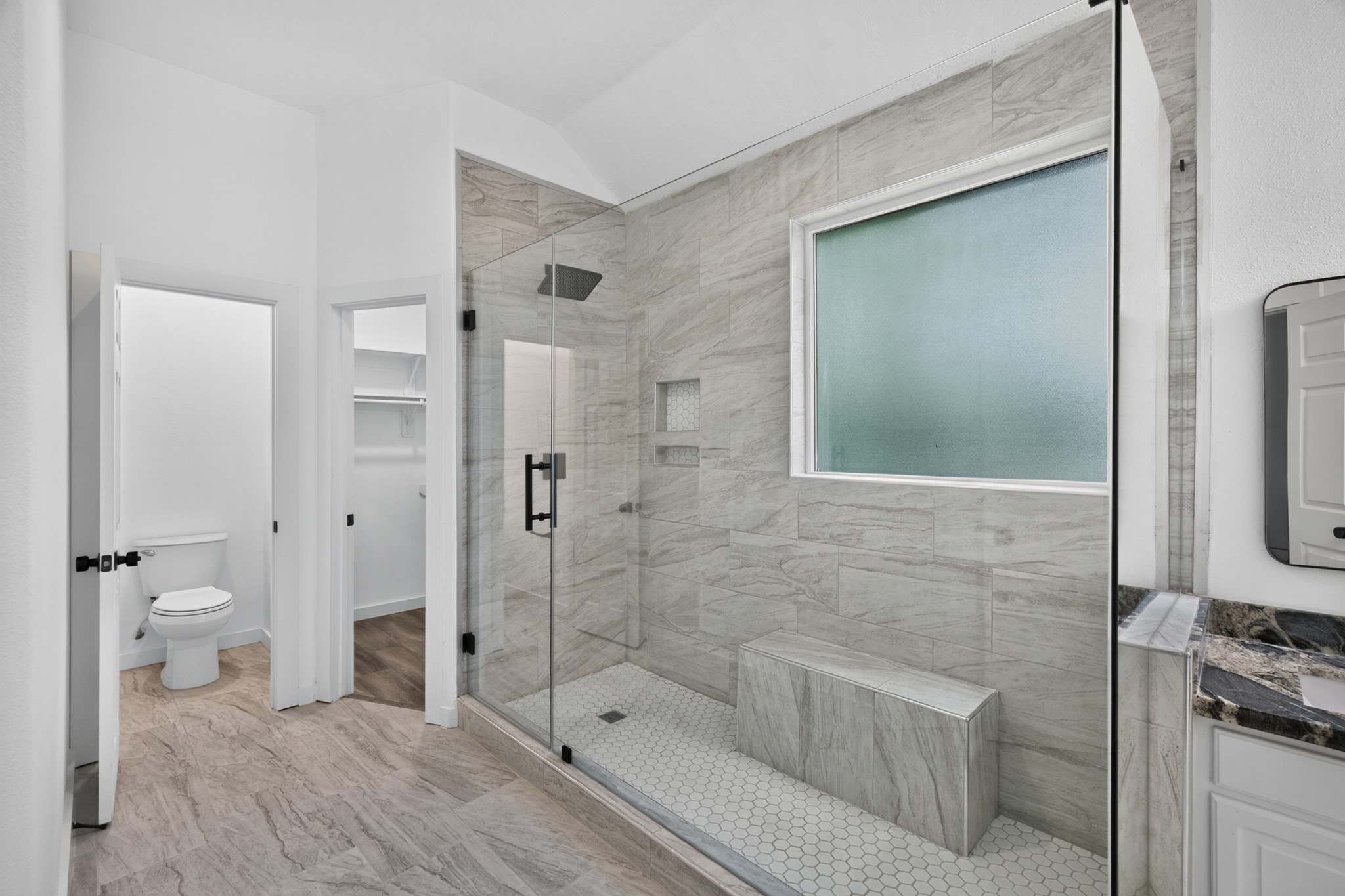 The spa-inspired bathroom at 18 Griffin Hill Court features beautiful floor-to-ceiling tile work, a spacious walk-in shower with glass enclosure, and a clean modern aesthetic. Every detail has been carefully selected to create a tranquil retreat where you can relax and recharge  a true escape from the demands of everyday life.