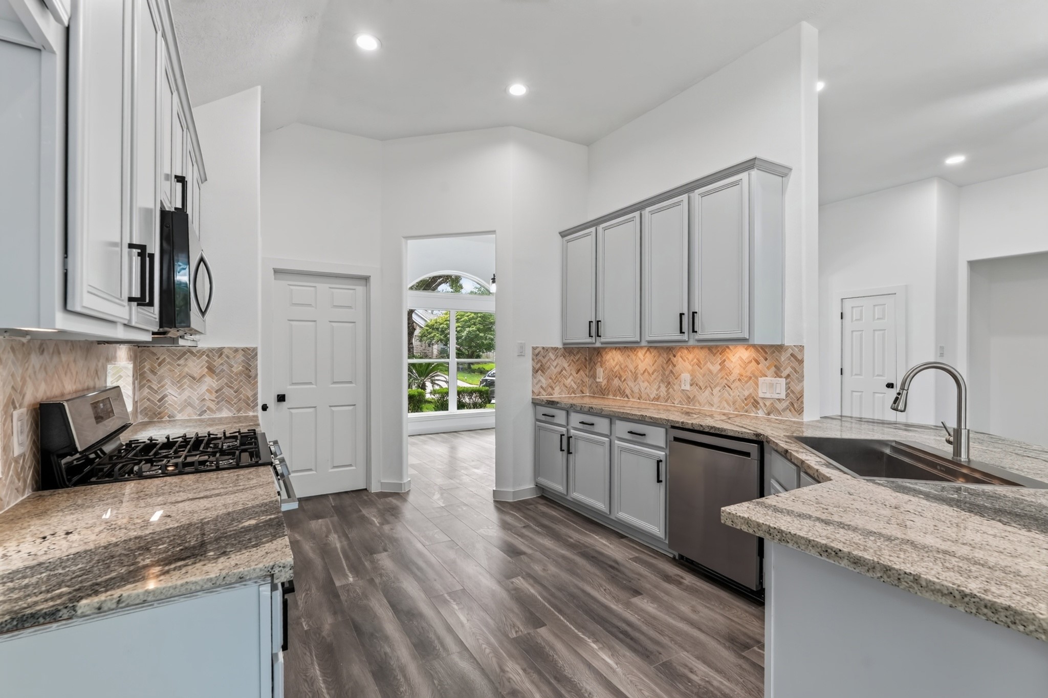 Premium stainless steel appliances and beautiful teal backsplash tiles take center stage in this kitchen view at 18 Griffin Hill Court. A range with stainless hood, refrigerator, and dishwasher are thoughtfully integrated into the cabinetry, combining impeccable style and high performance for a truly chef-worthy cooking and entertaining experience.