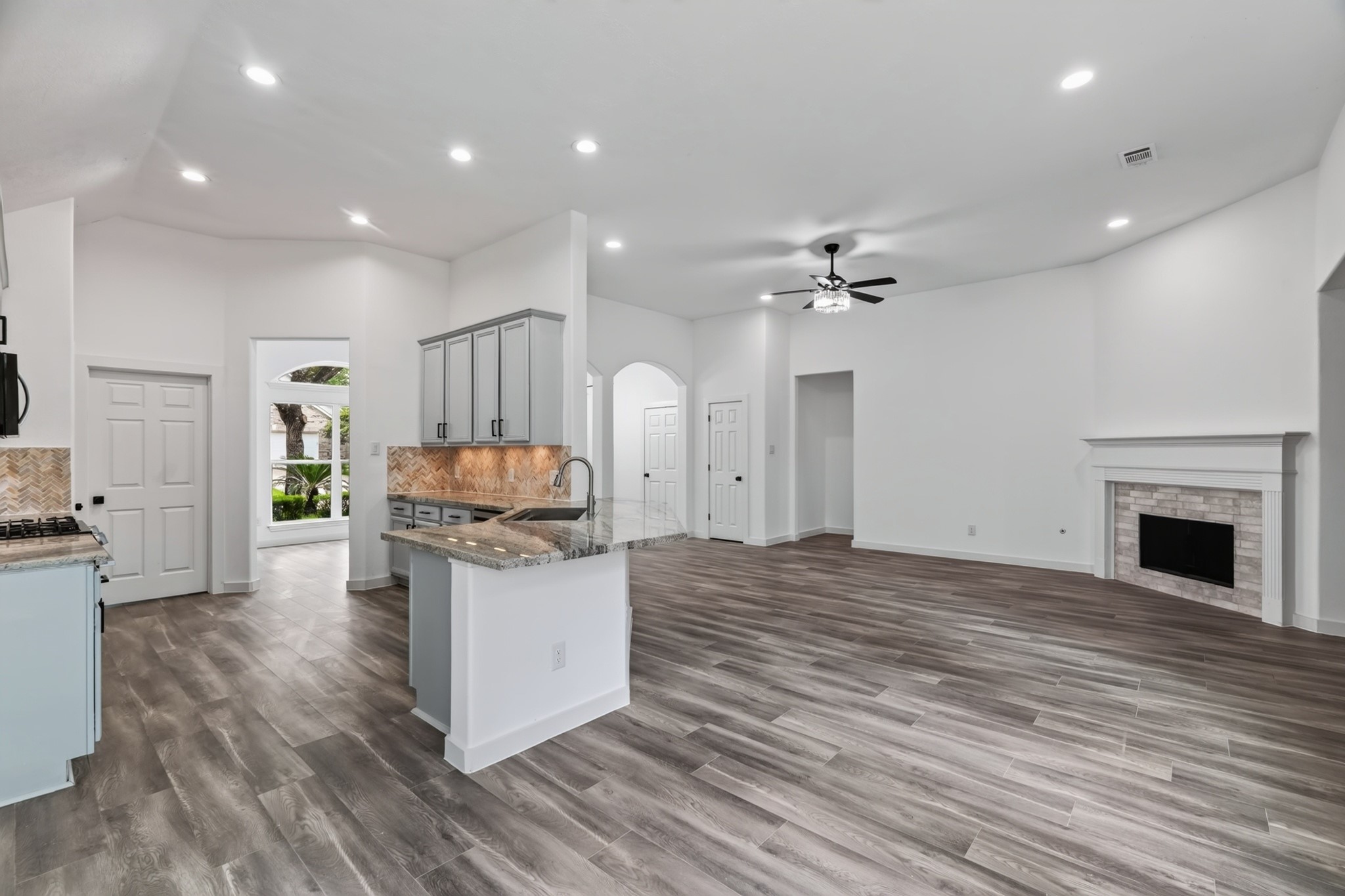 A wide-angle view of the family room at 18 Griffin Hill Court captures the home's impressive open-concept layout. The ceiling fan, handsome fireplace focal point, and seamless flow between living and dining areas create a warm and inviting atmosphere  perfect for everyday family life and for entertaining guests in comfort and style.