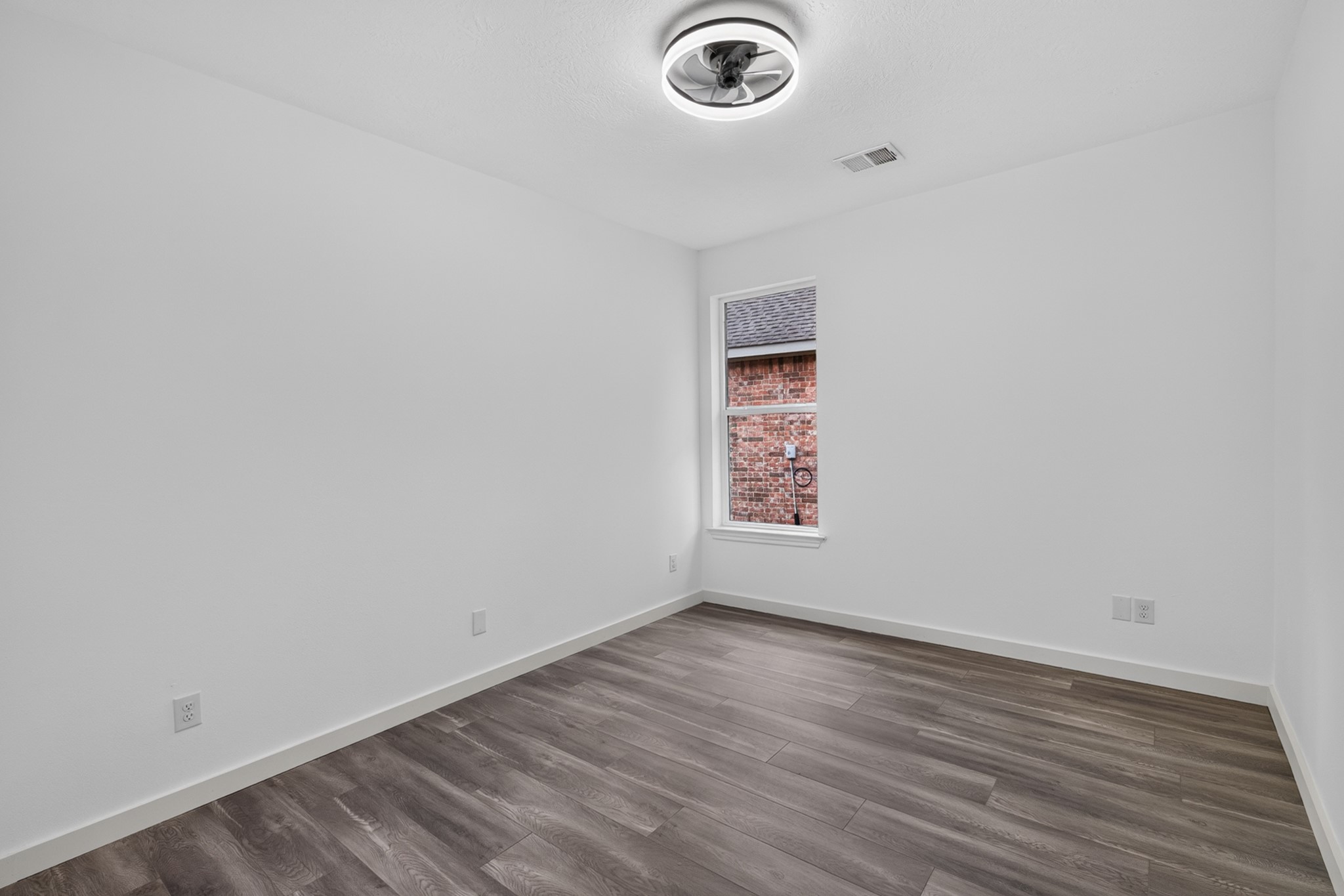 A cozy secondary bedroom at 18 Griffin Hill Court provides comfortable proportions, pristine white walls, and dark hardwood-style flooring throughout. Whether used as a children's room, guest bedroom, or home office, this versatile space adapts easily to meet your family's evolving needs  ready to be personalized with your own unique style and vision.