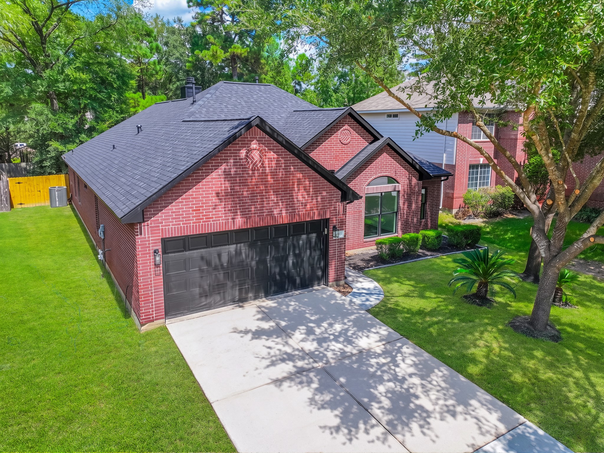 A different perspective of 18 Griffin Hill Court's charming exterior reveals the home's generous proportions and well-maintained brick construction. The lush green lawn, manicured landscaping, and attached two-car garage are visible from this angle, showcasing the property's excellent curb appeal and pride of ownership.