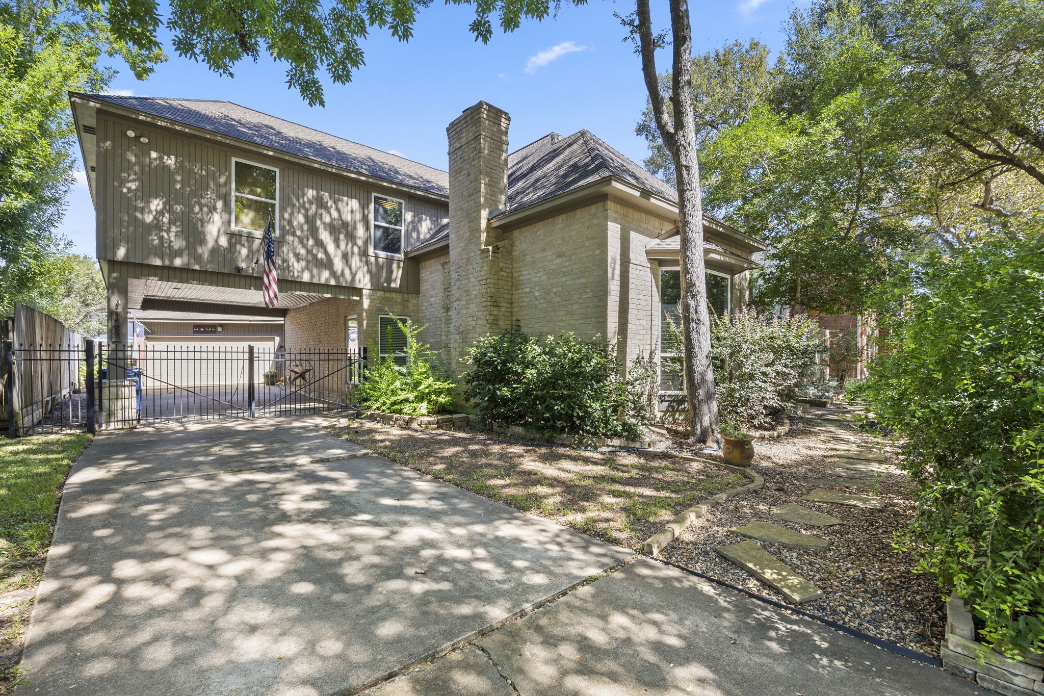 An extended driveway leads to a portce cochere and detached garage, while mature trees, established landscaping, and a combination of brick and siding add to the home's distinctive exterior character.