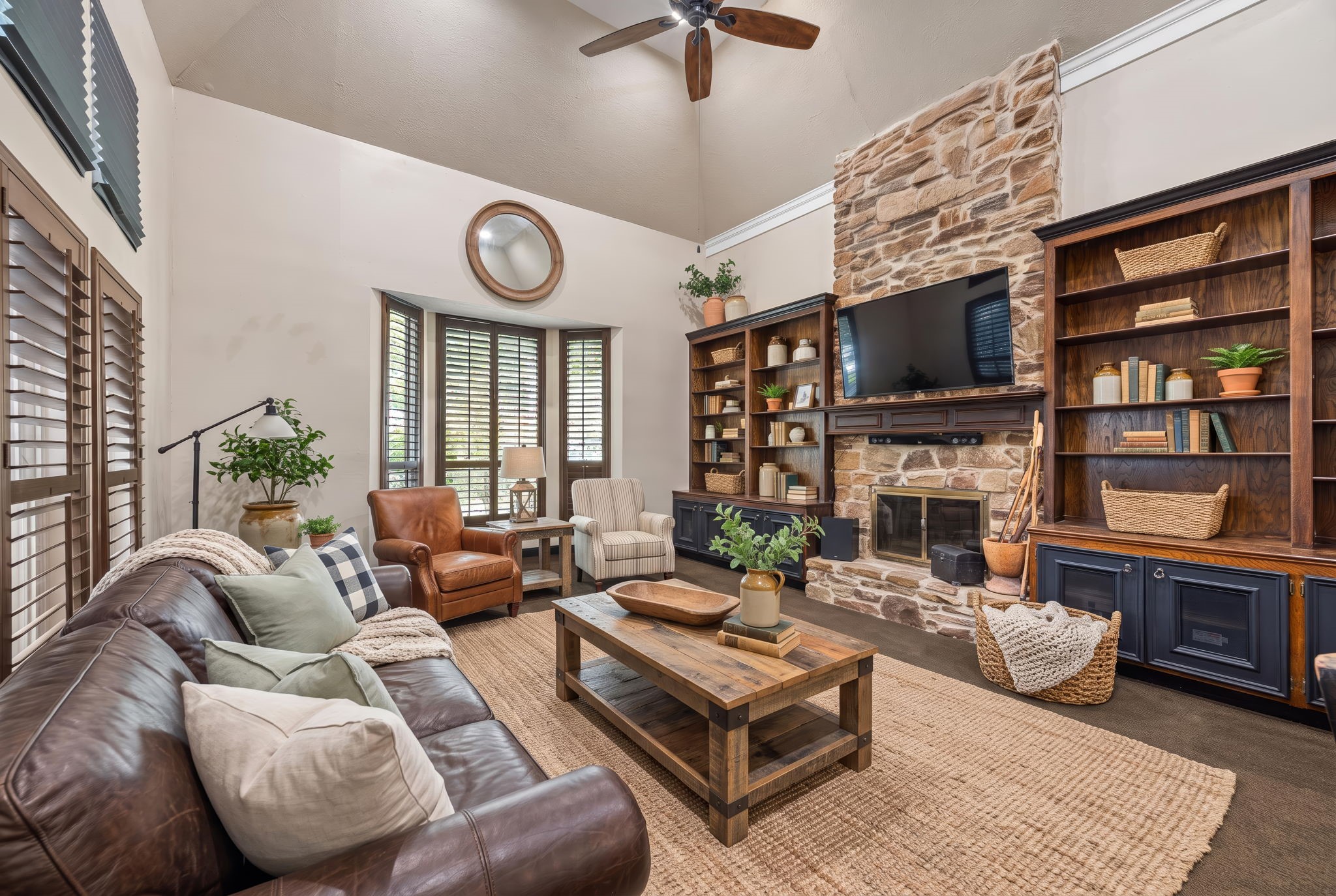Virtually staged to illustrate an alternative furniture arrangement, this view highlights the stone fireplace, custom built-ins with lower cabinetry, and charming bay window overlooking the front landscaping.