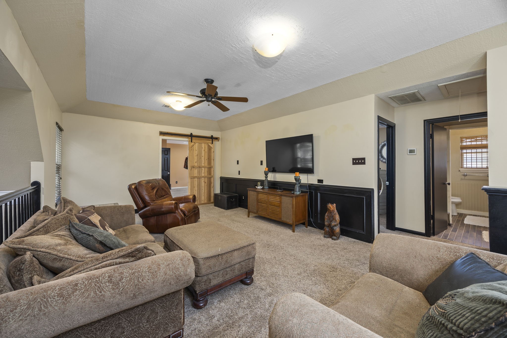 Another view of the game room highlights the generous floor space, flexible furniture arrangement, and convenient access to the adjoining room and bathroom.