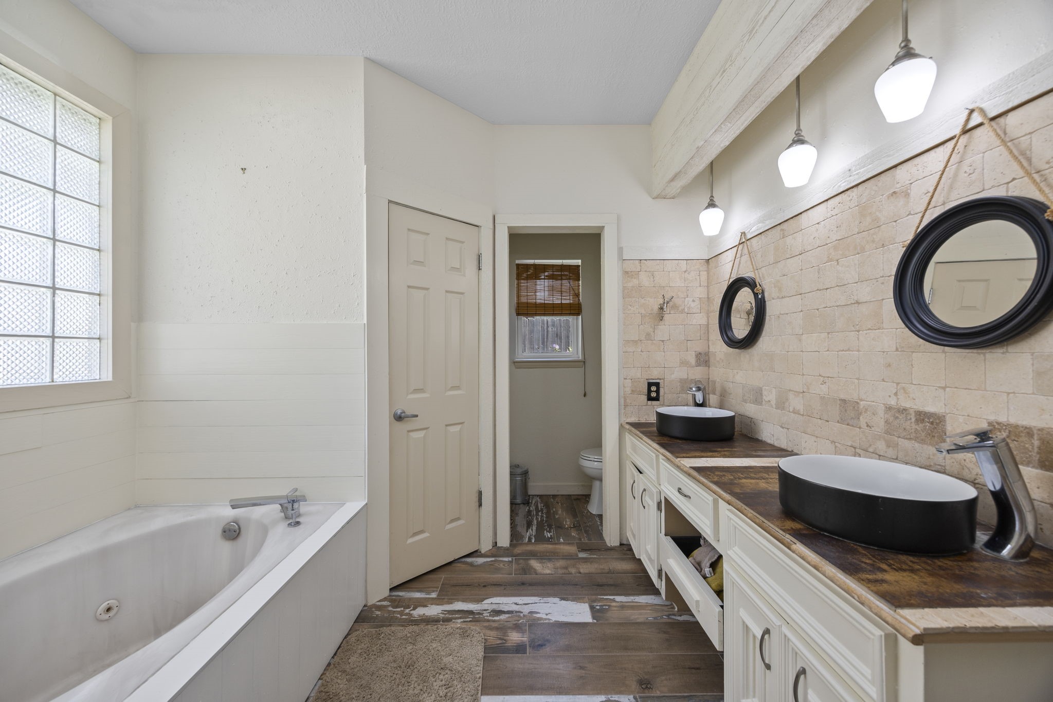 The primary bathroom features a spacious vanity with dual above-counter vessel sinks, a full-size soaking tub, and a separate walk-in shower. Generous counter space and cabinetry provide practical storage and convenience for everyday routines.