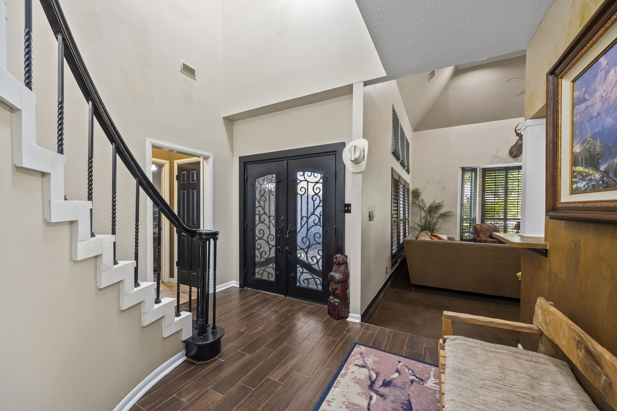Step inside to discover soaring ceilings, wood flooring, and a gracefully curved staircase with contrasting dark railing. The open foyer offers a glimpse into the living spaces beyond.