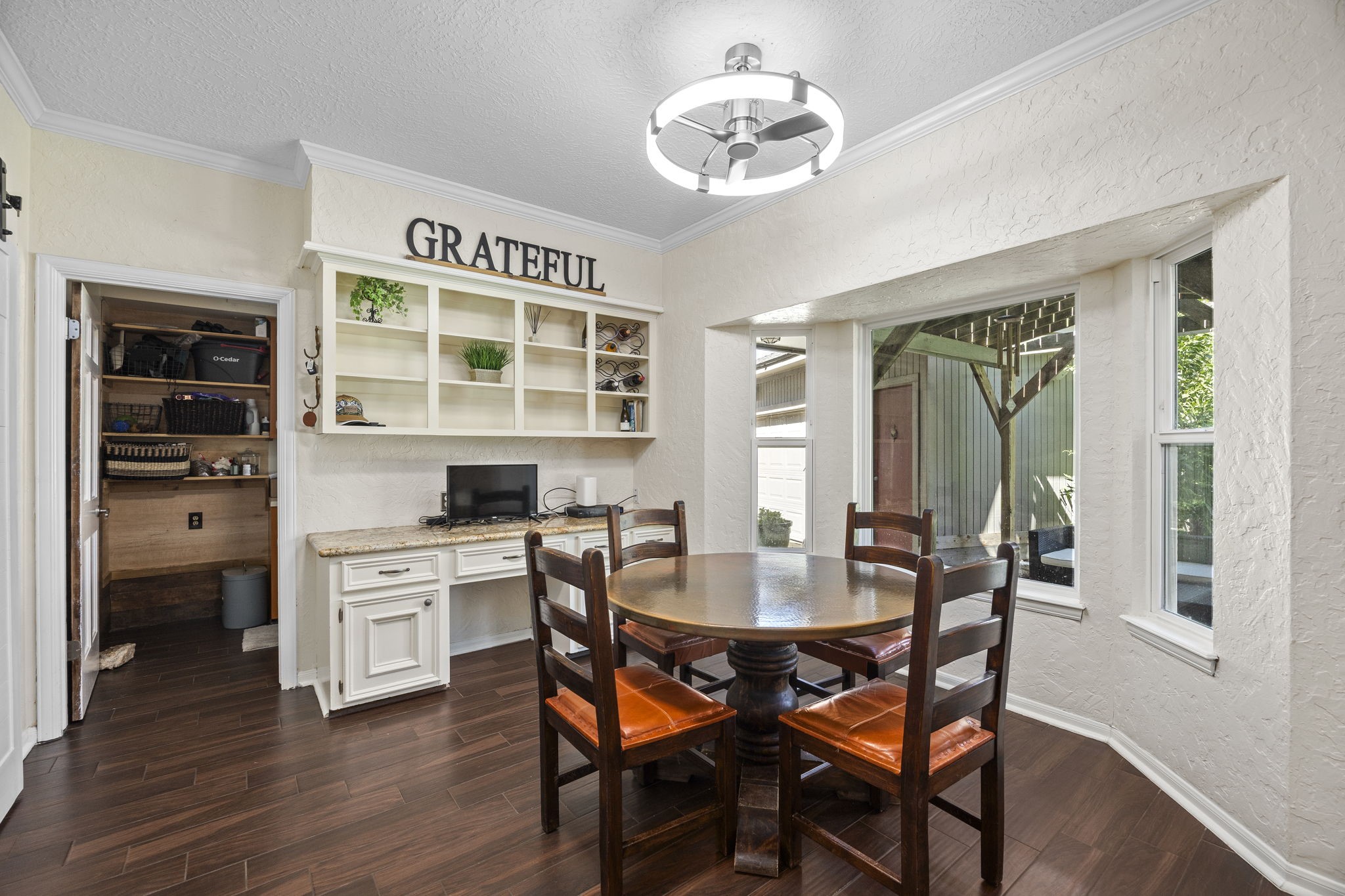 Another view of the breakfast room highlights the built-in desk and shelving, offering convenient space for organization, cookbooks, or a household workstation. Direct access to the laundry room adds everyday functionality to this area of the home.