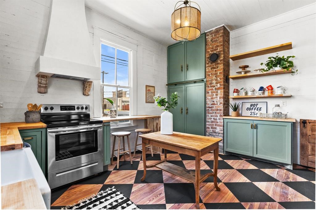 Beautifully updated kitchen featuring updated vent hood, butchers block countertops, painted hardwood floors and tons of storage!
