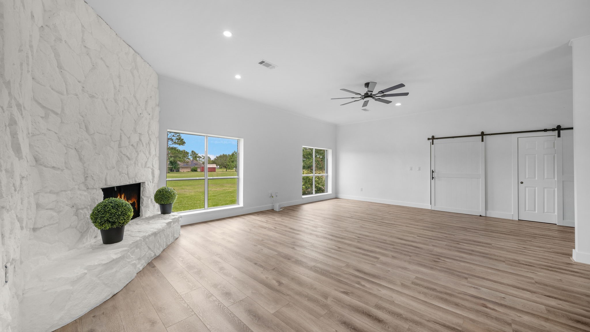 Family Room with wood burning fireplace, Barn doors closing off leads to Primary Bedroom hall and hall of 2 secondary bedrooms and bath