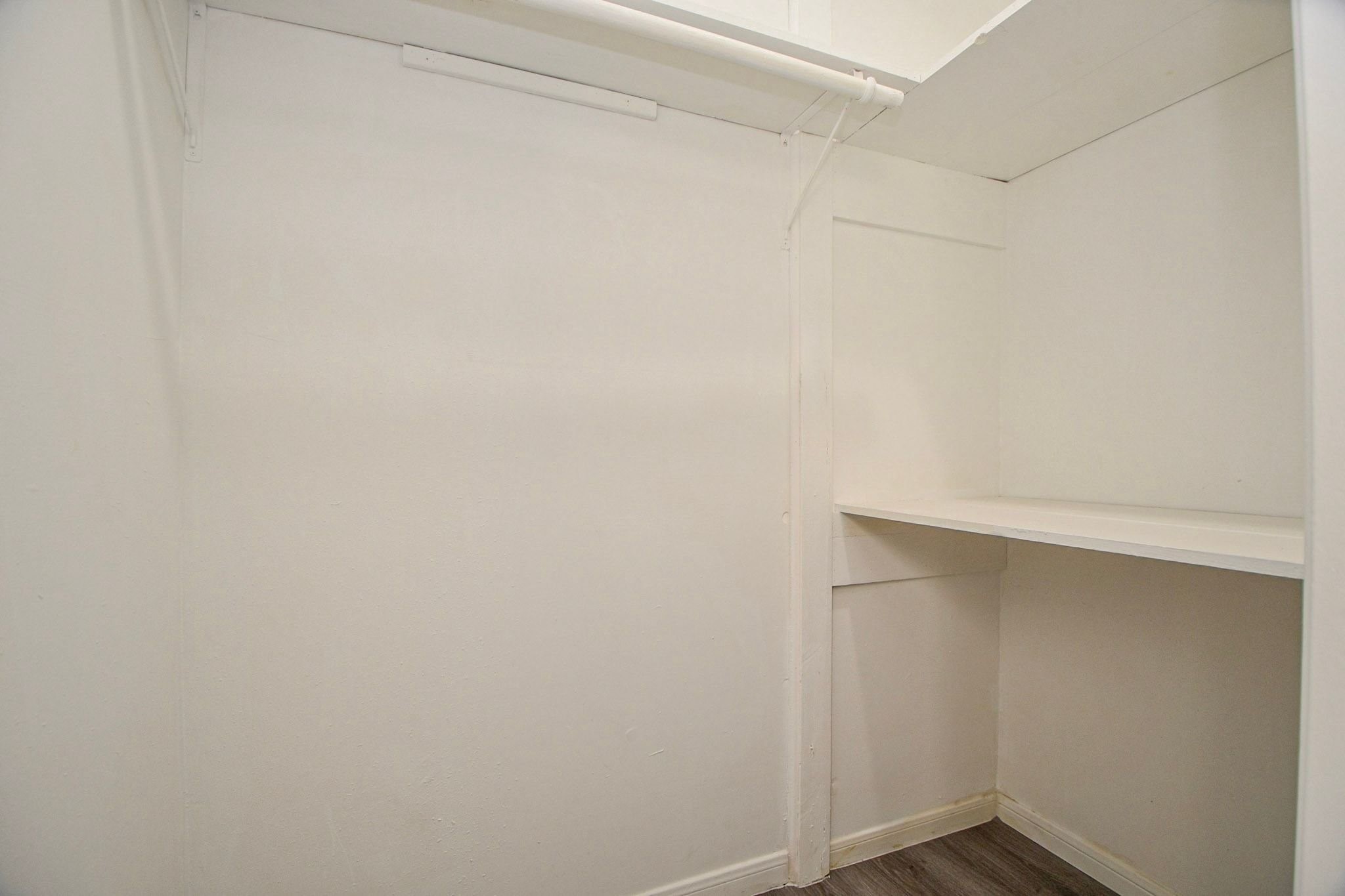 Walk-in closet features built-in shelving and a hanging rod for convenient clothing storage.