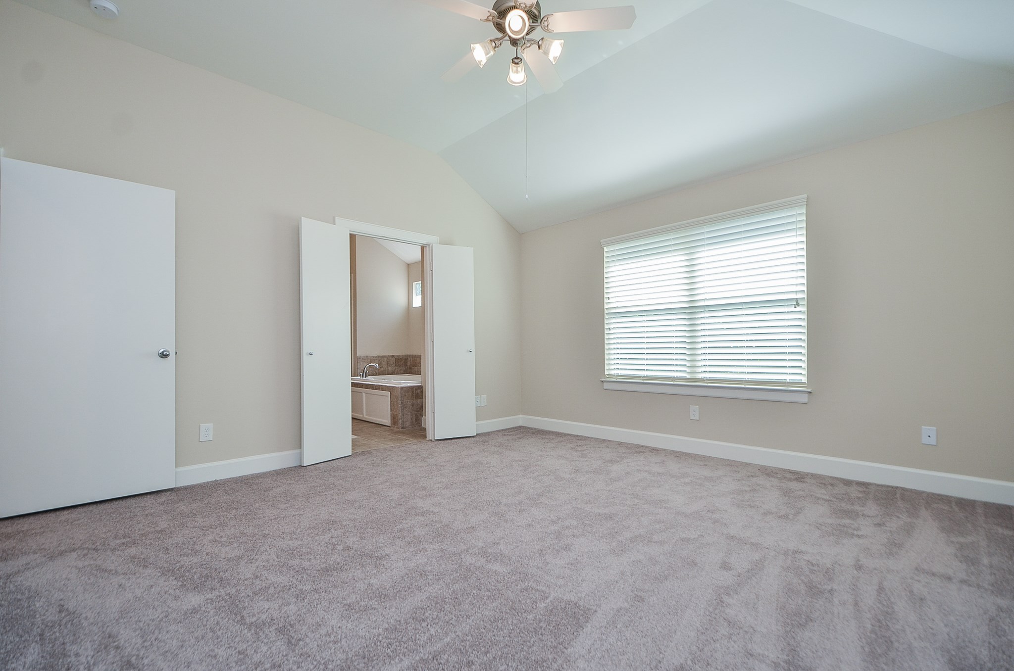 The master bedroom has plush carpet, hight ceilings, a ceiling fan, pre-installed blinds, and plenty of natural light.
