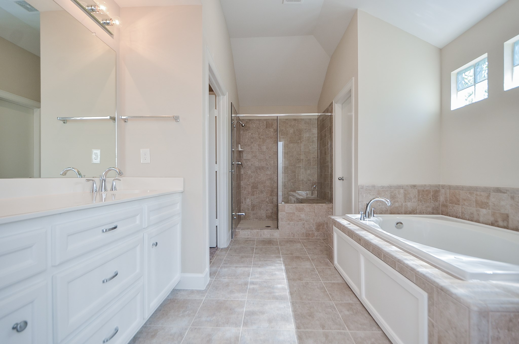 Tile flooring, an oversized walk in shower, dual sinks, pull out drawers, white cabinets, and a massive jetted tub are some of the features you will enjoy in the master bathroom.