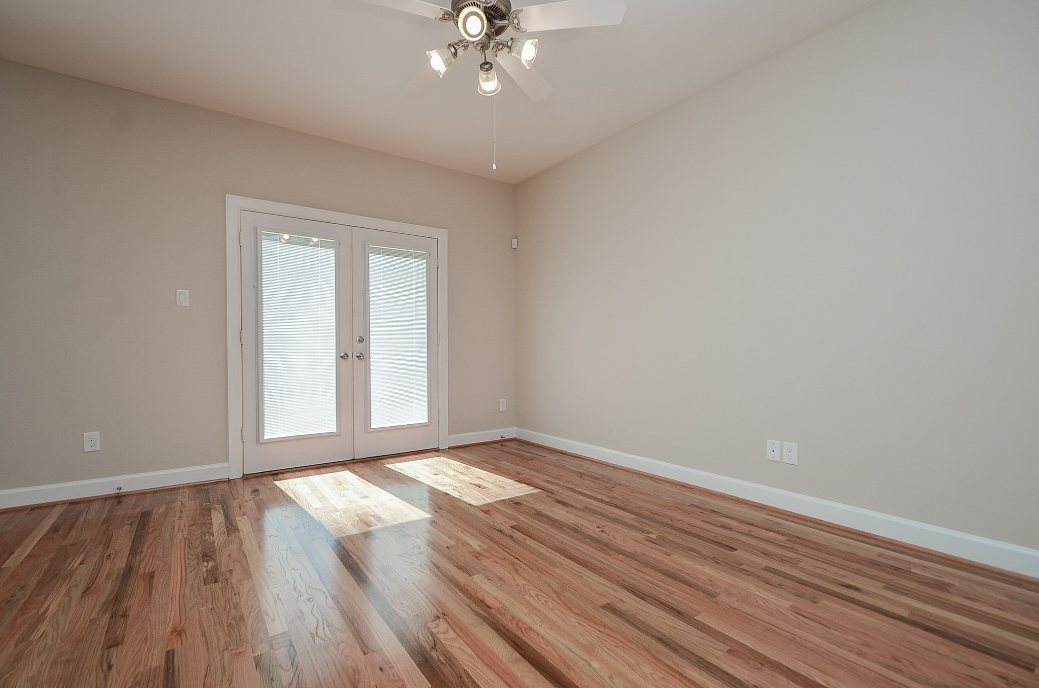 Double doors in the living area lead into the spacious backyard.  Neutral paint, a ceiling fan, and gleaming red oak floors accentuate the living area.