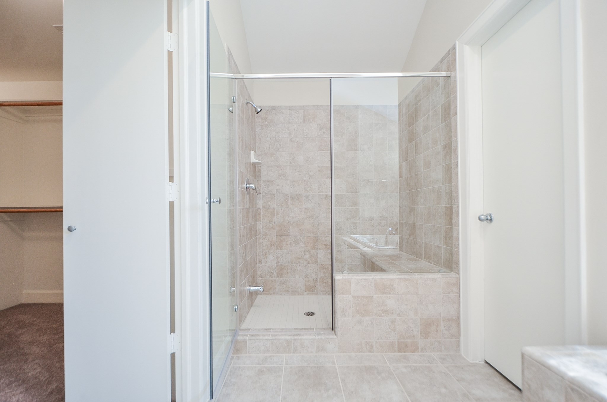 Additional view of the shower with the closet to the left and toilet behind the closed door.