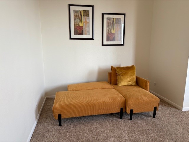 Cozy corner featuring a stylish mustard chaise lounge against a neutral wall, accented by modern artwork above, offering a perfect spot to relax.