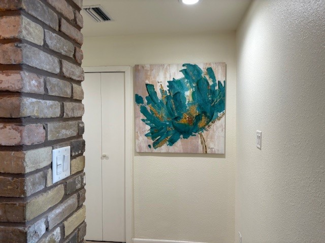 Charming hallway featuring a rustic brick accent wall and vibrant artwork, adding a touch of color and character.