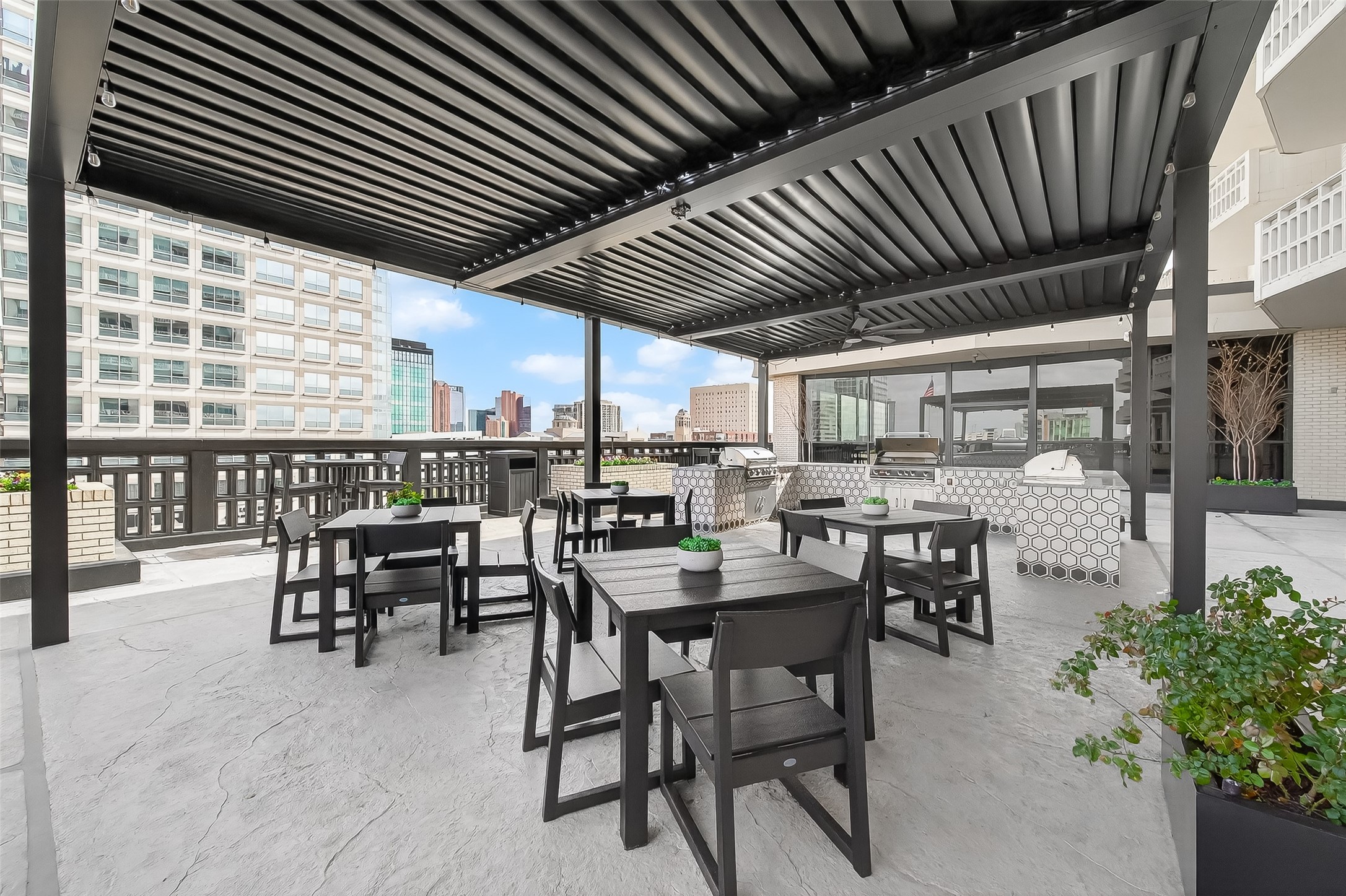Stylish outdoor terrace featuring a covered seating area with modern furniture and a built-in grill, perfect for entertaining with stunning city views.