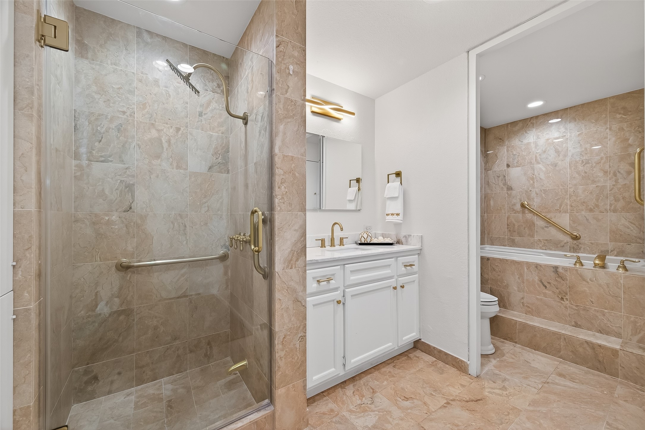 Luxurious bathroom featuring elegant marble tiling, a spacious glass-enclosed shower, and a cozy soaking tub for ultimate relaxation.