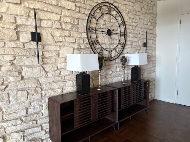 Chic entryway featuring a striking stone accent wall, elegant modern sconces, and a stylish console with contemporary lamps, creating a welcoming and sophisticated atmosphere.