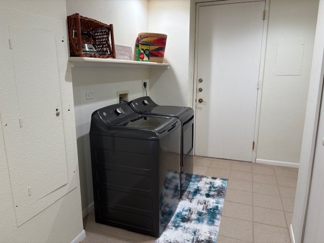 Modern laundry area with sleek black appliances, built-in shelving, and convenient tile flooring, offering functionality and style.