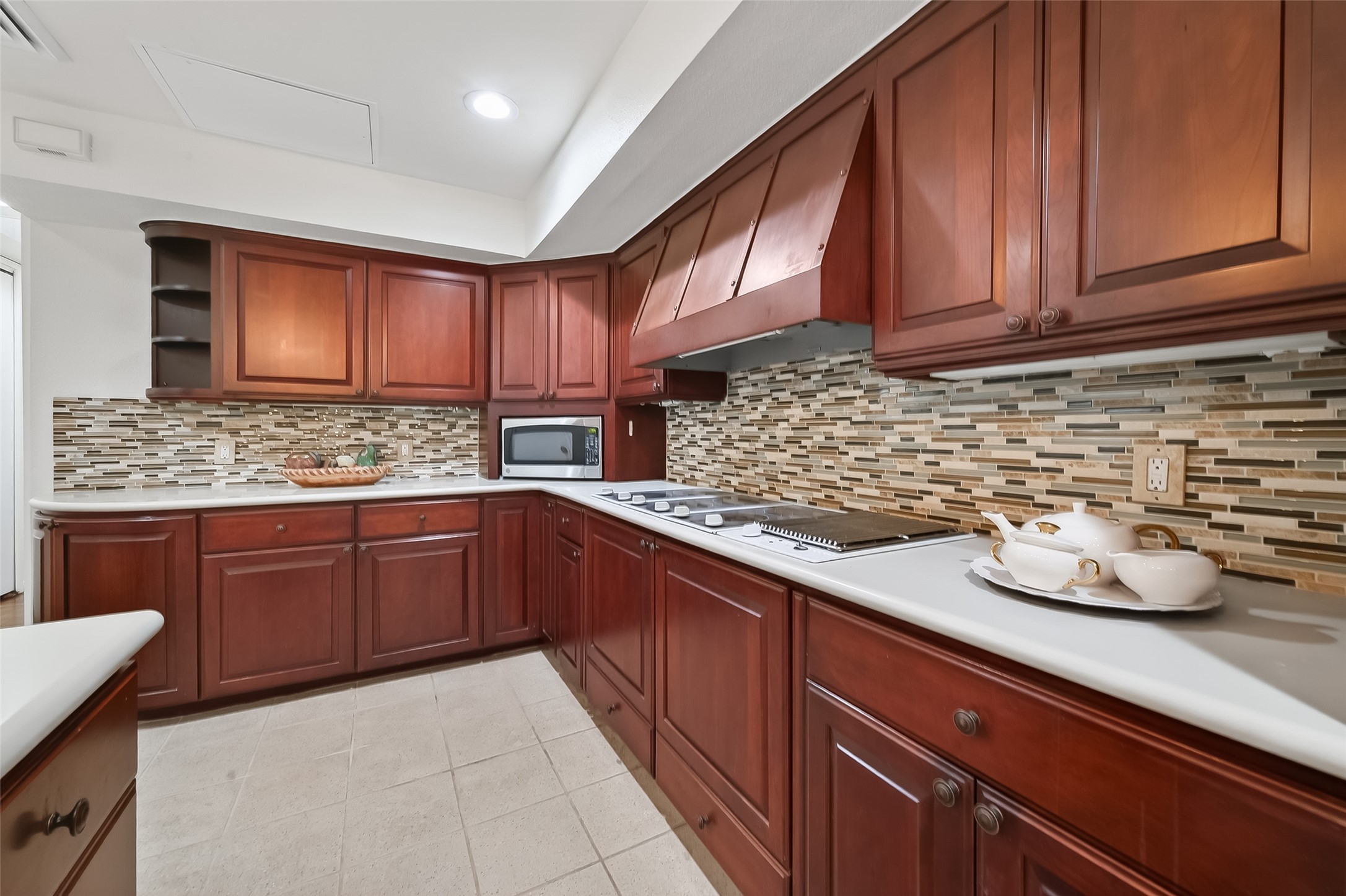 Elegant kitchen featuring rich wooden cabinetry, sleek countertops, and a stylish mosaic tile backsplash, creating a warm and inviting cooking space.