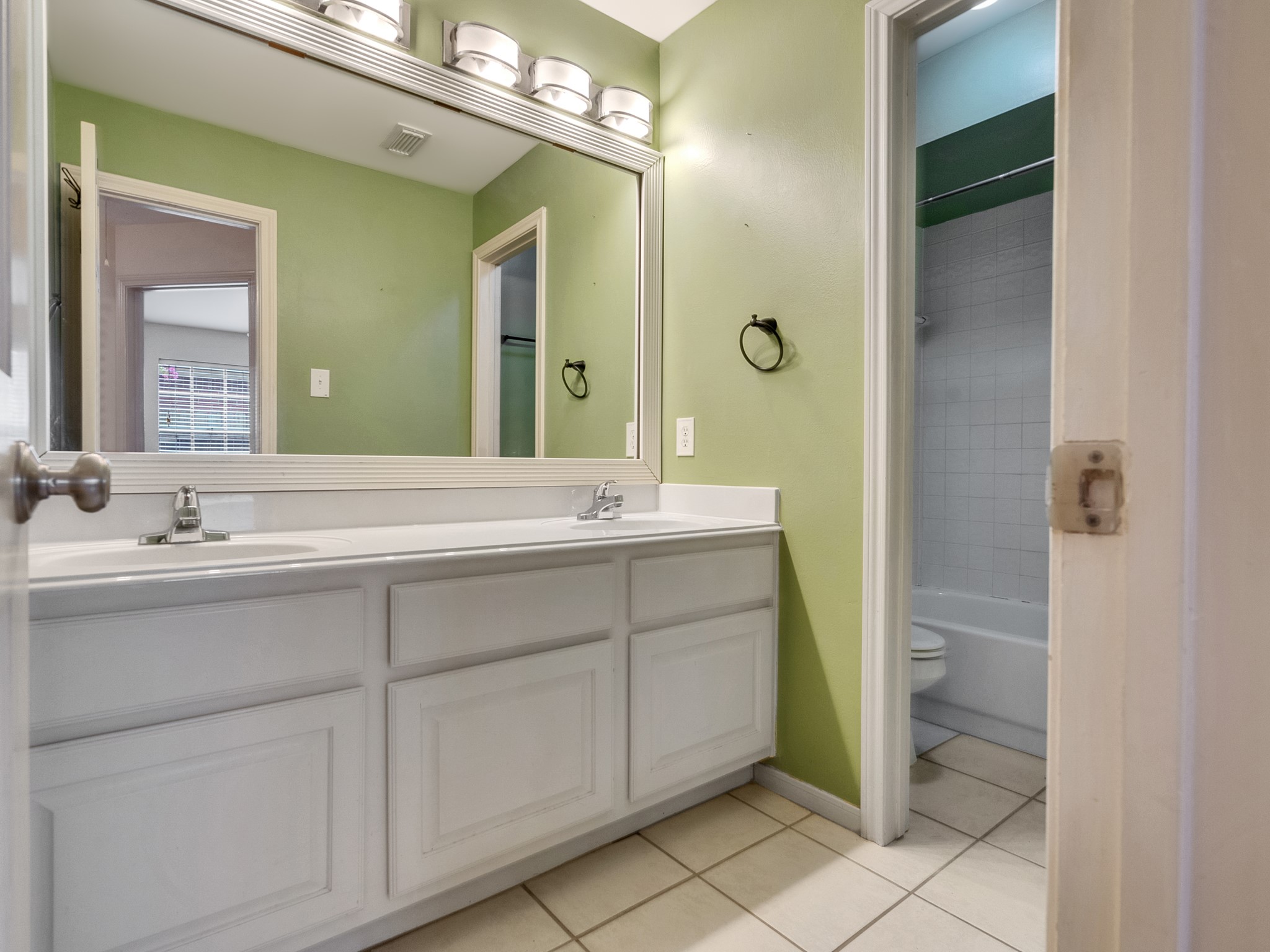 View of the full bath with double sink and water closet for extra privacy