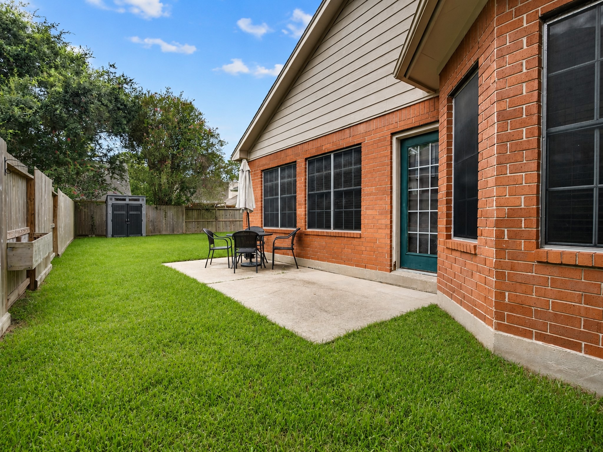 View of the backyard patio space - Storage shed conveys with the home