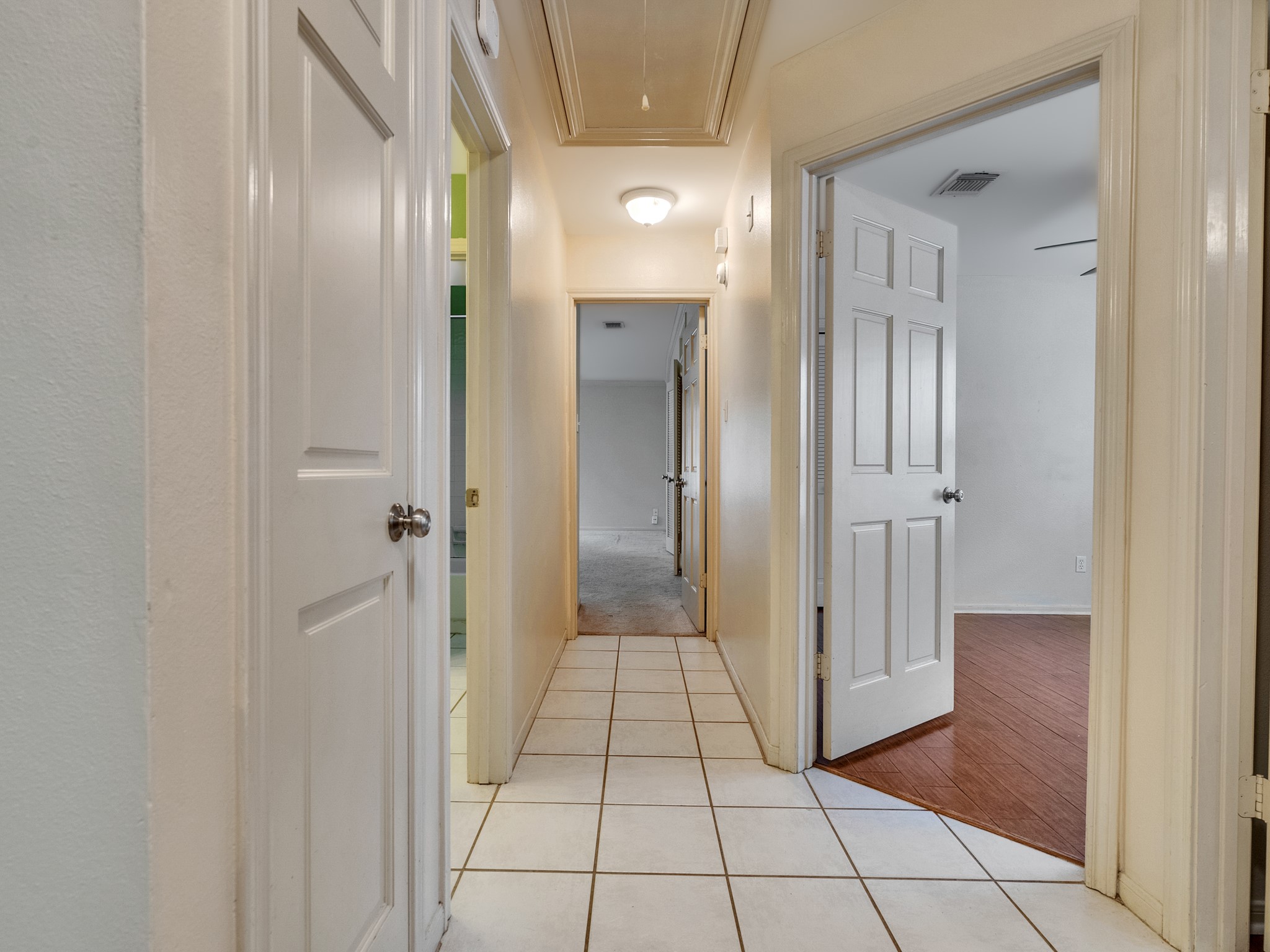 Hallway leading to the second and primary bedrooms. Full bath on the left between the secondary bedrooms