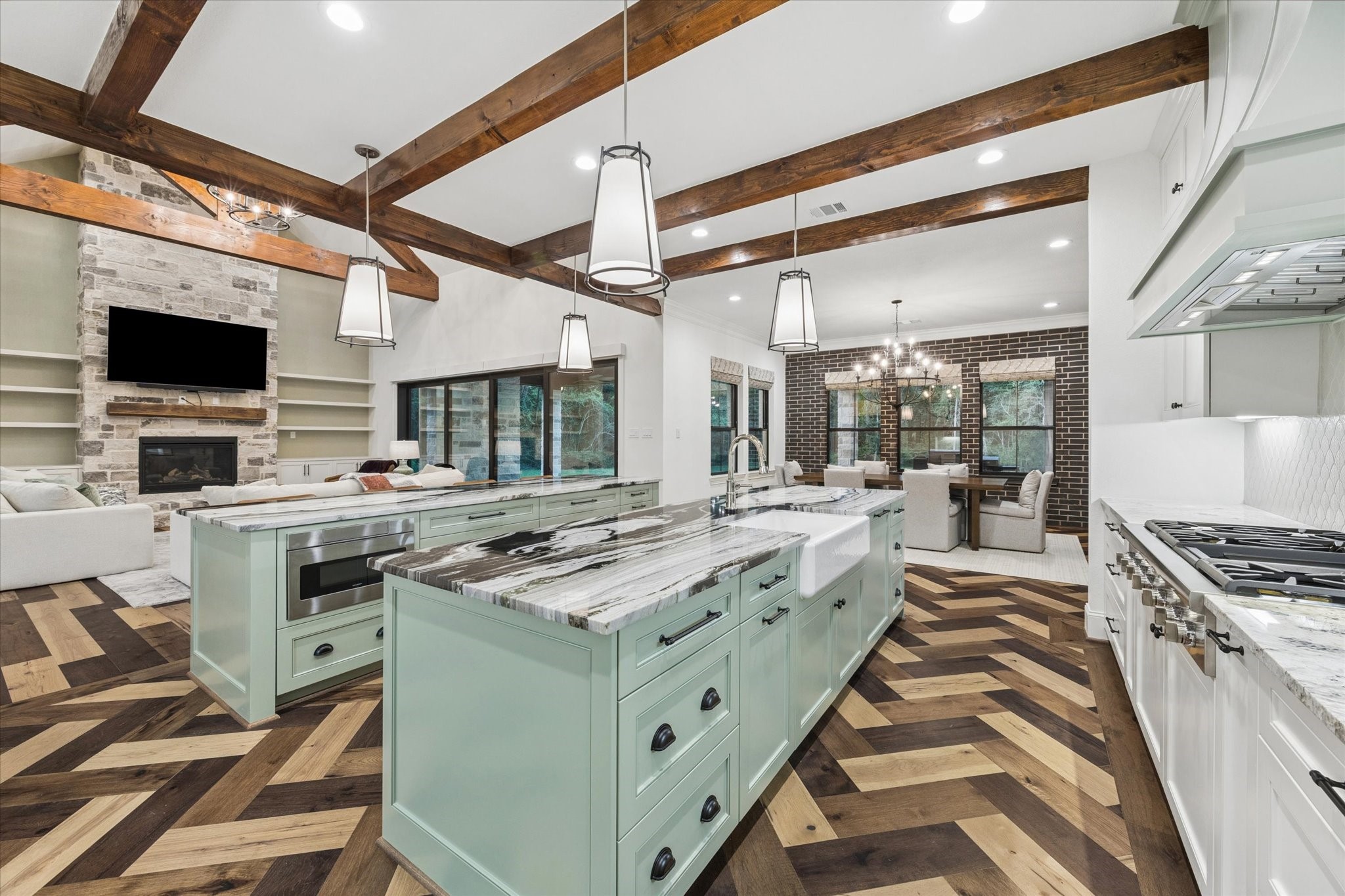 The oversized gathering island provides generous seating and serves as the social heart of this exceptional chefs kitchen. Fantasy Zebra marble introduces dramatic natural movement, while custom sage-green cabinetry and rich wood ceiling beams add warmth and character. The kitchen also features paneled appliance integration, two refrigerators with freezers, two dishwashers, double ovens, a warming drawer, built-in microwave, and an impressive six-burner Thermador cooktop with integrated griddle.