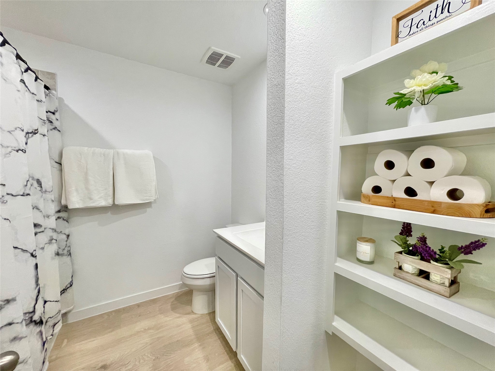 Immaculate guest bathroom featuring smart, custom built-in shelving for flawless linen storage and easy organization.