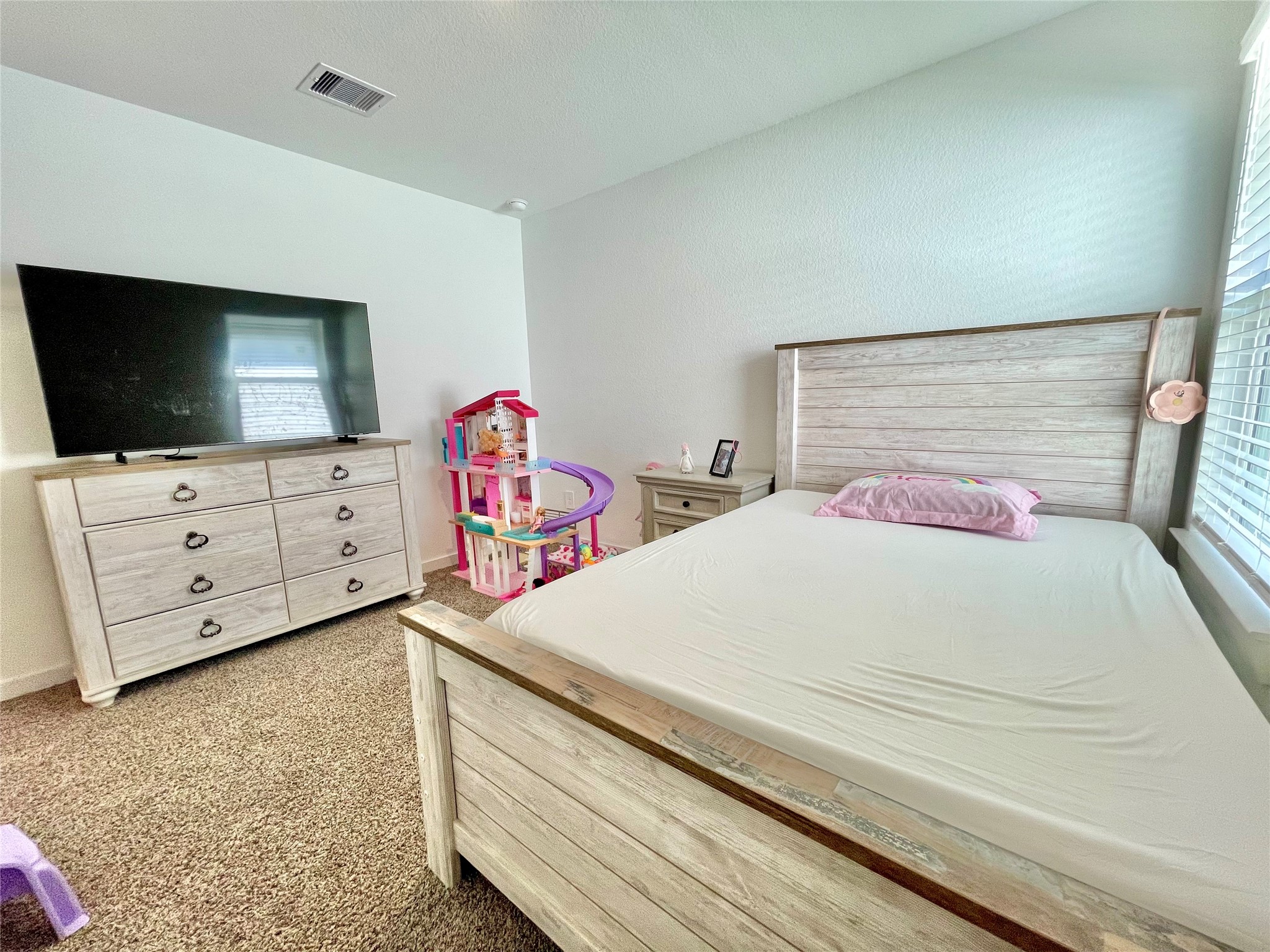 A bright and spacious secondary bedroom, beautifully styled as a charming kid's room with ample space for a full bedroom set.