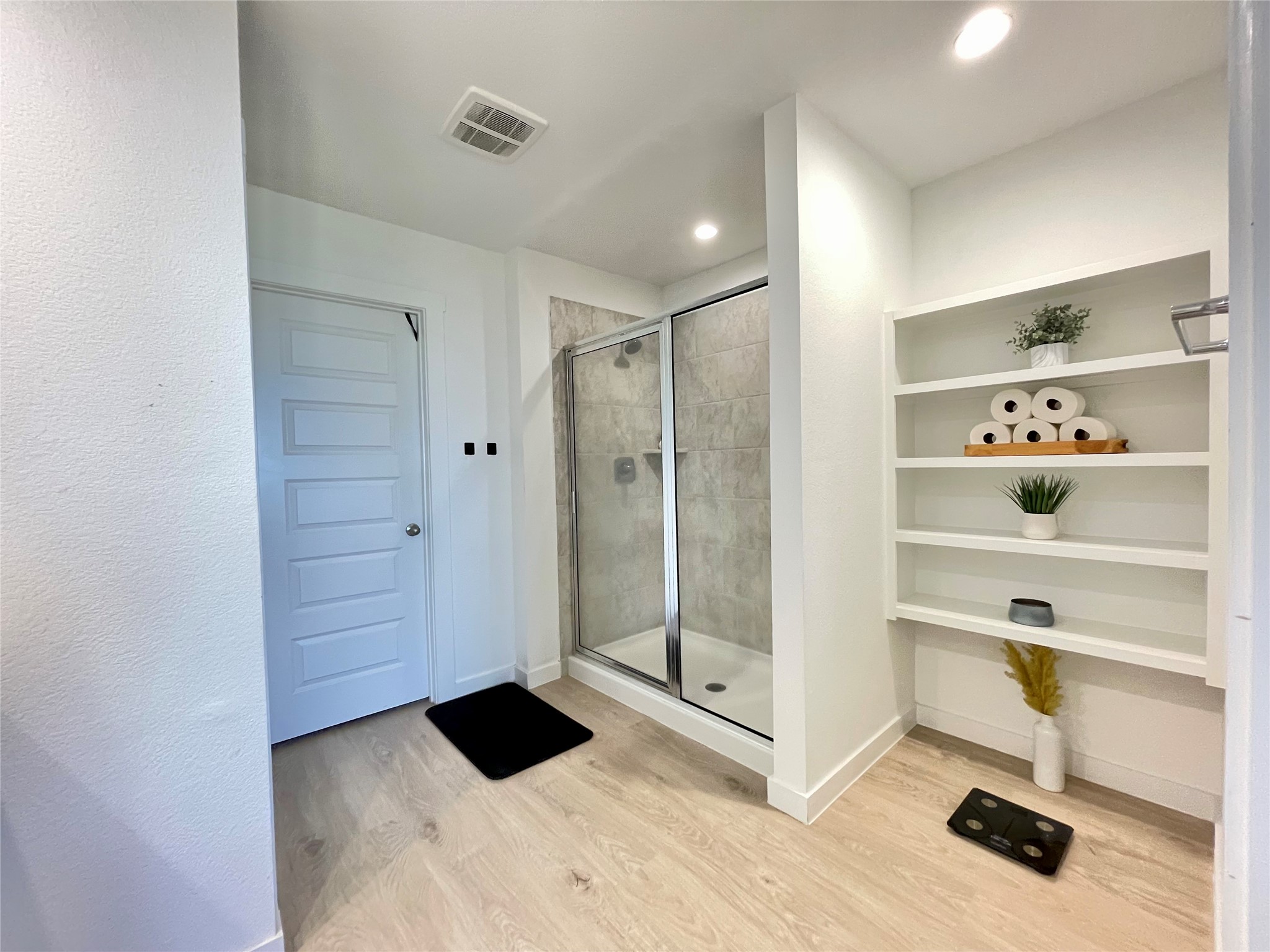 Impeccable design meets daily functionality with easy access to the walk-in glass shower and custom built-in shelving.
