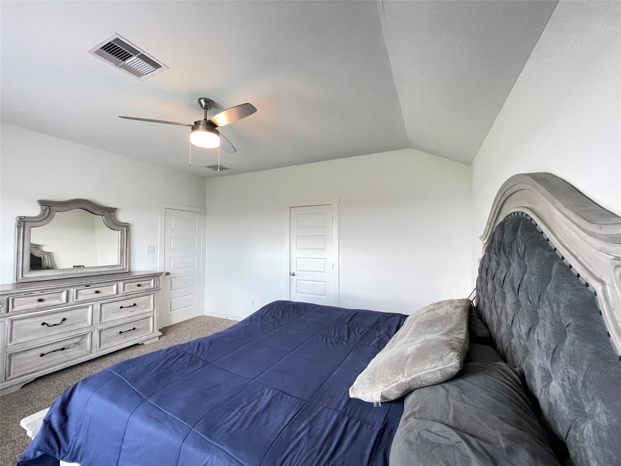 Another perspective of the expansive primary bedroom showcases its soaring ceilings and ample space for king-sized furniture.