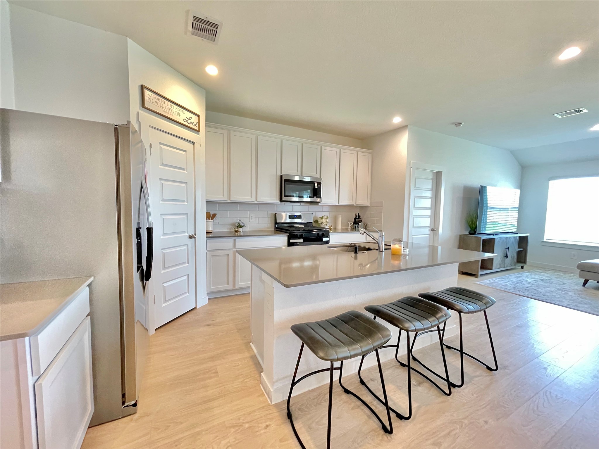 A chefs dream! The gourmet kitchen boasts pristine white cabinetry, high-end stainless steel appliances, and a massive central island.
