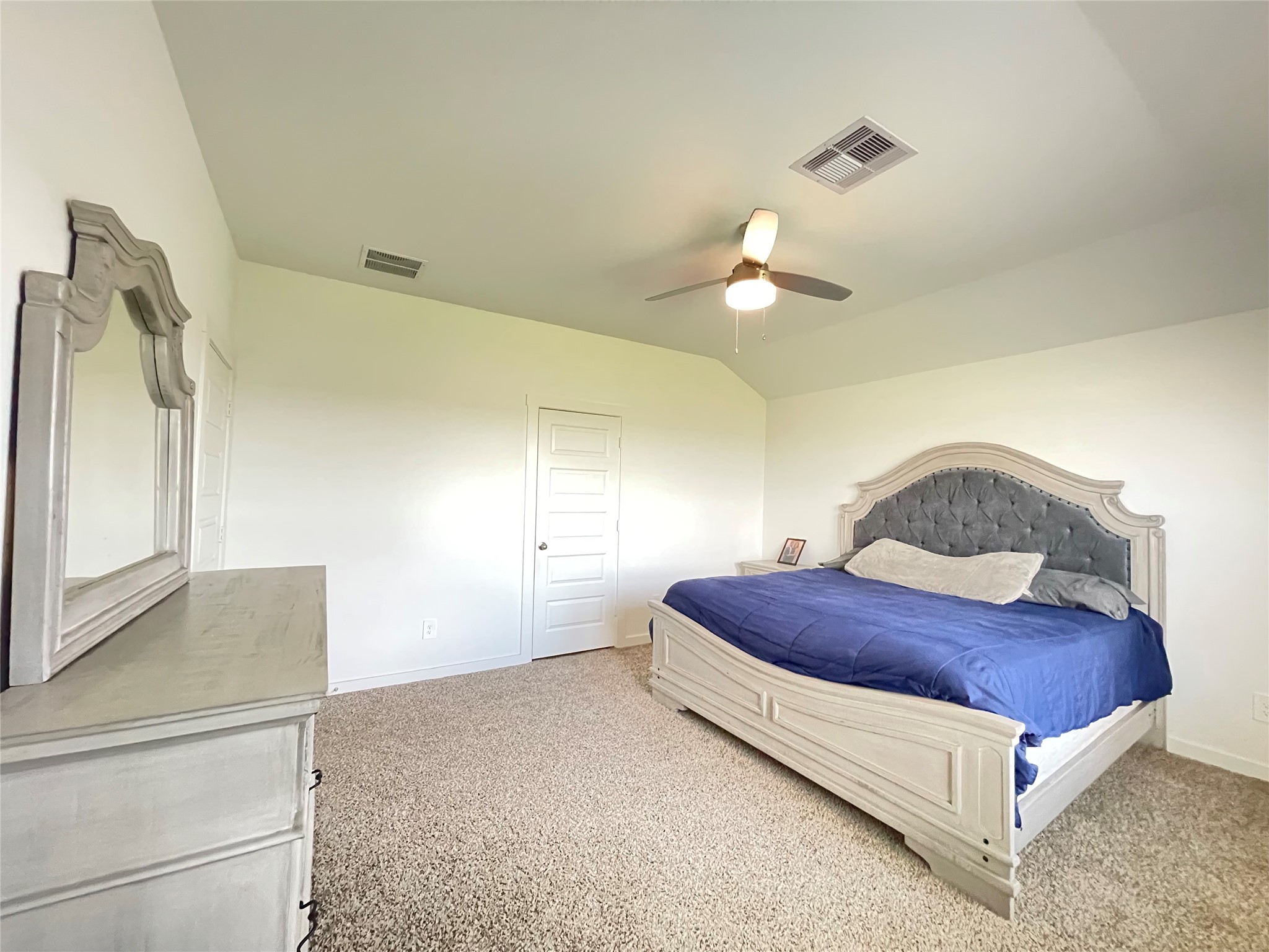 Retreat to the grand primary suitea serene oasis designed for absolute rest, featuring plush carpeting and a cooling ceiling fan