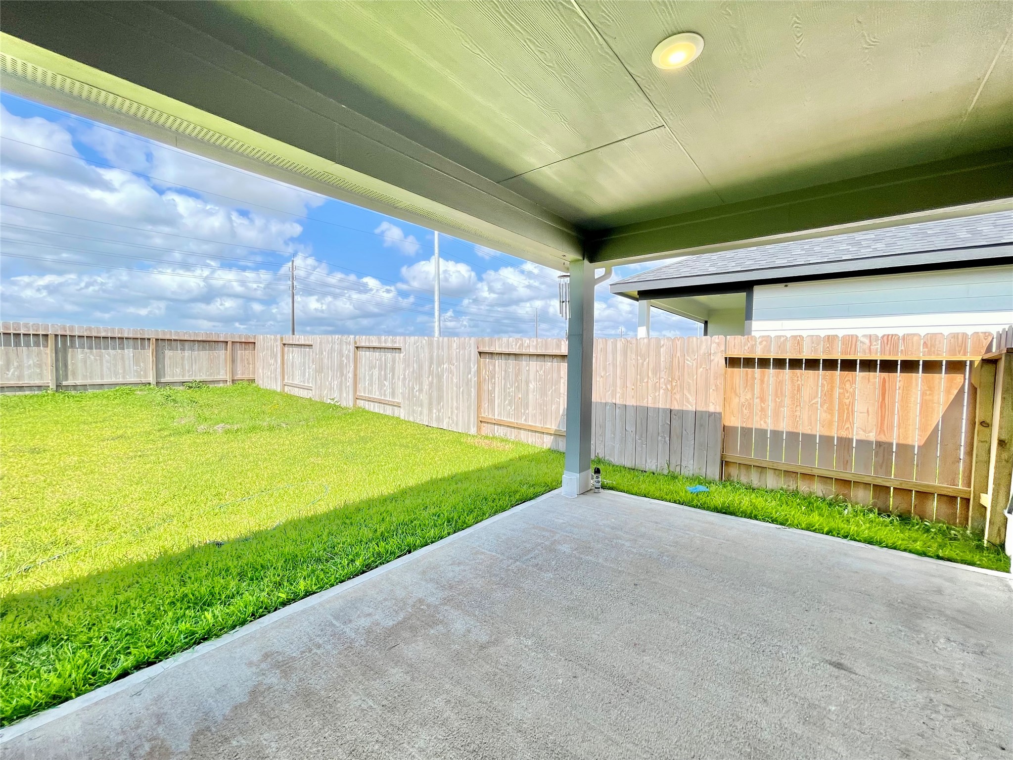 The deep, sheltered patio design provides the perfect shade while overlooking the lush, private green yard.