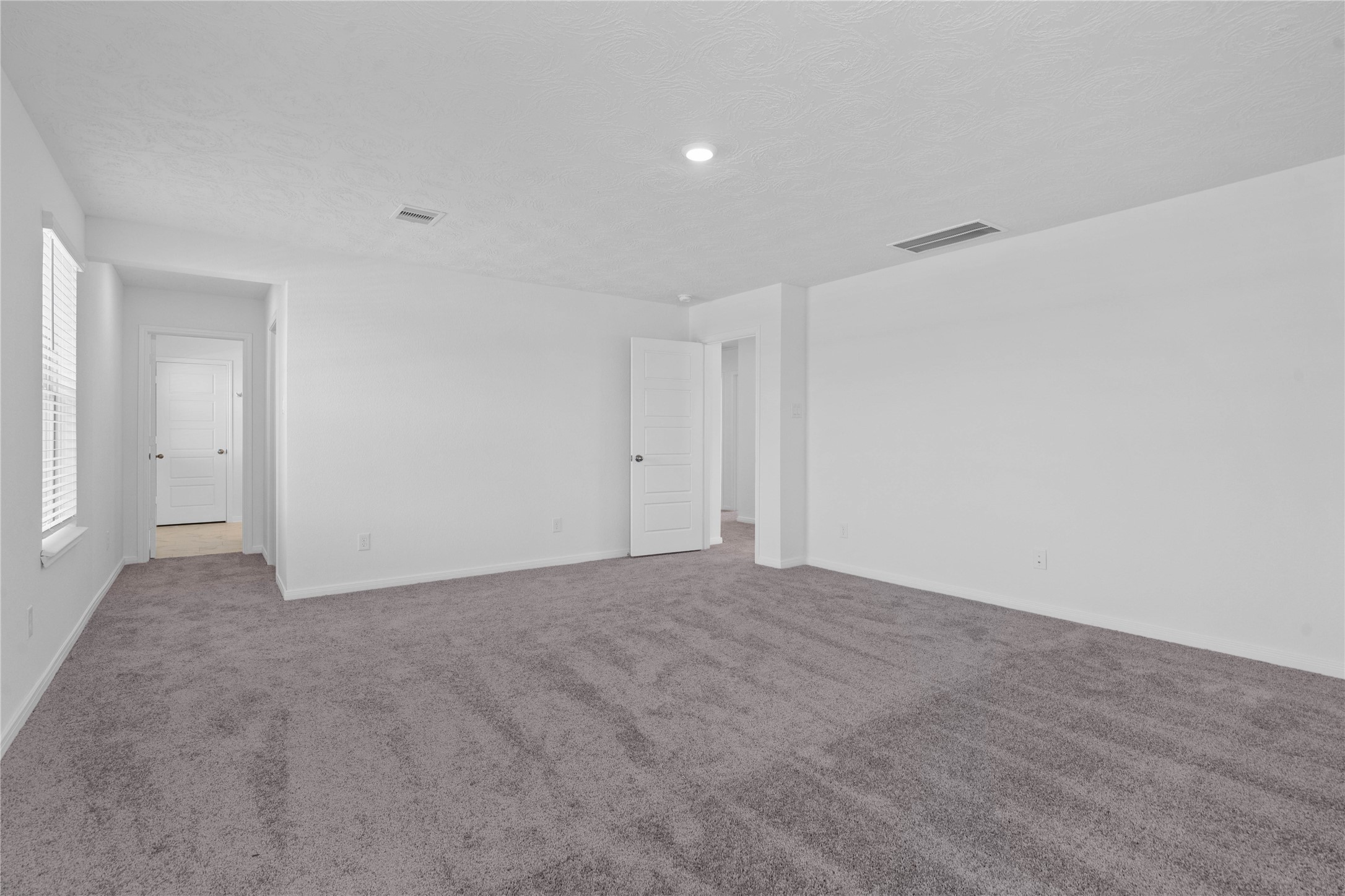 Come and unwind after a long day in this magnificent and spacious primary suite! This room features plush carpet, neutral paint, high ceiling, and large windows fitted with blinds.