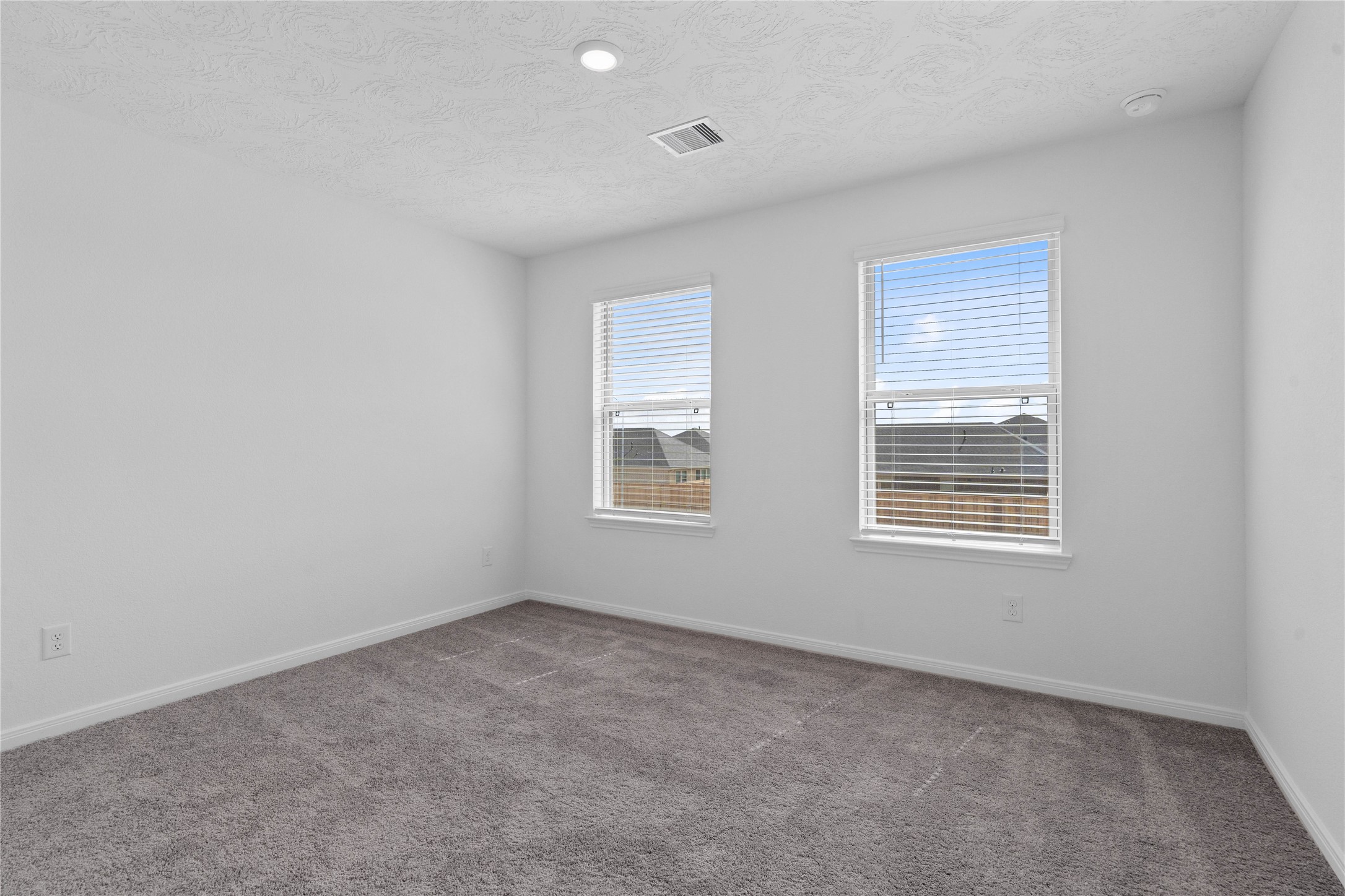 Secondary bedroom features plush carpet, neutral paint, recessed lighting, windows with blinds, and closet space.