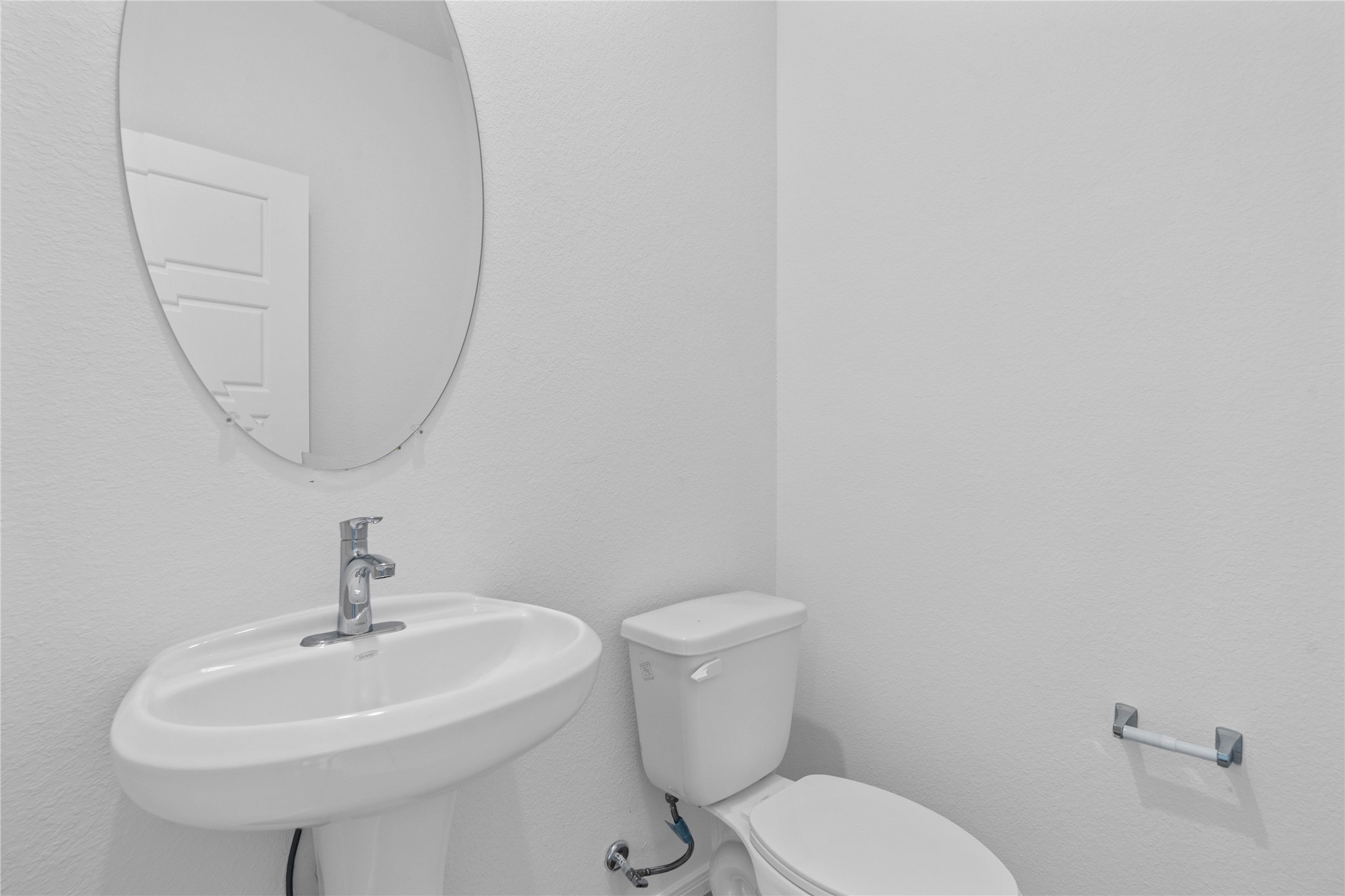 The powder bathroom features vinyl plank flooring, custom paint, pedestal sink with Moen faucet, and oval mirror.