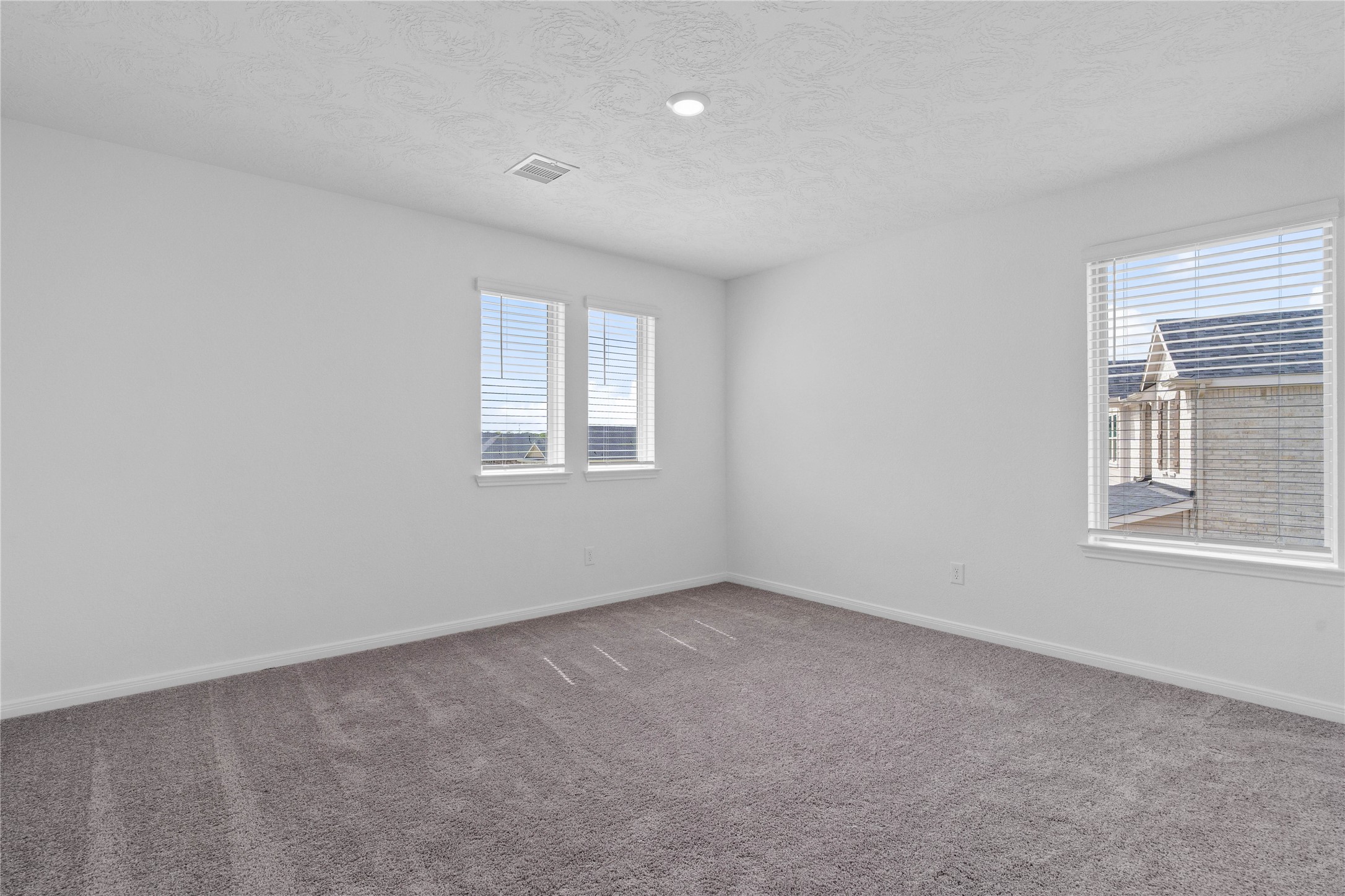 This secondary bedroom offers comfort and style with plush carpeting, neutral paint tones, recessed lighting, large windows with blinds, and closet.