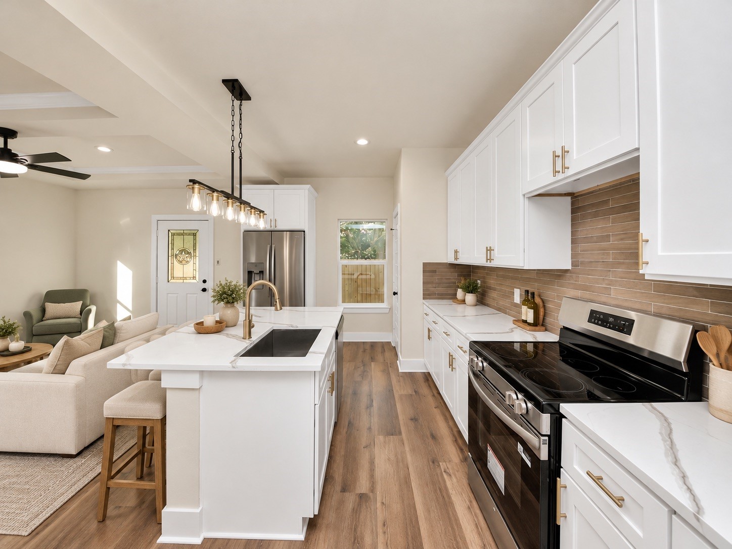 Spacious kitchen featuring a large center island with undermount sink, modern fixtures, soft-close cabinets & drawers, and an open layout overlooking the main living area | Virtually staged