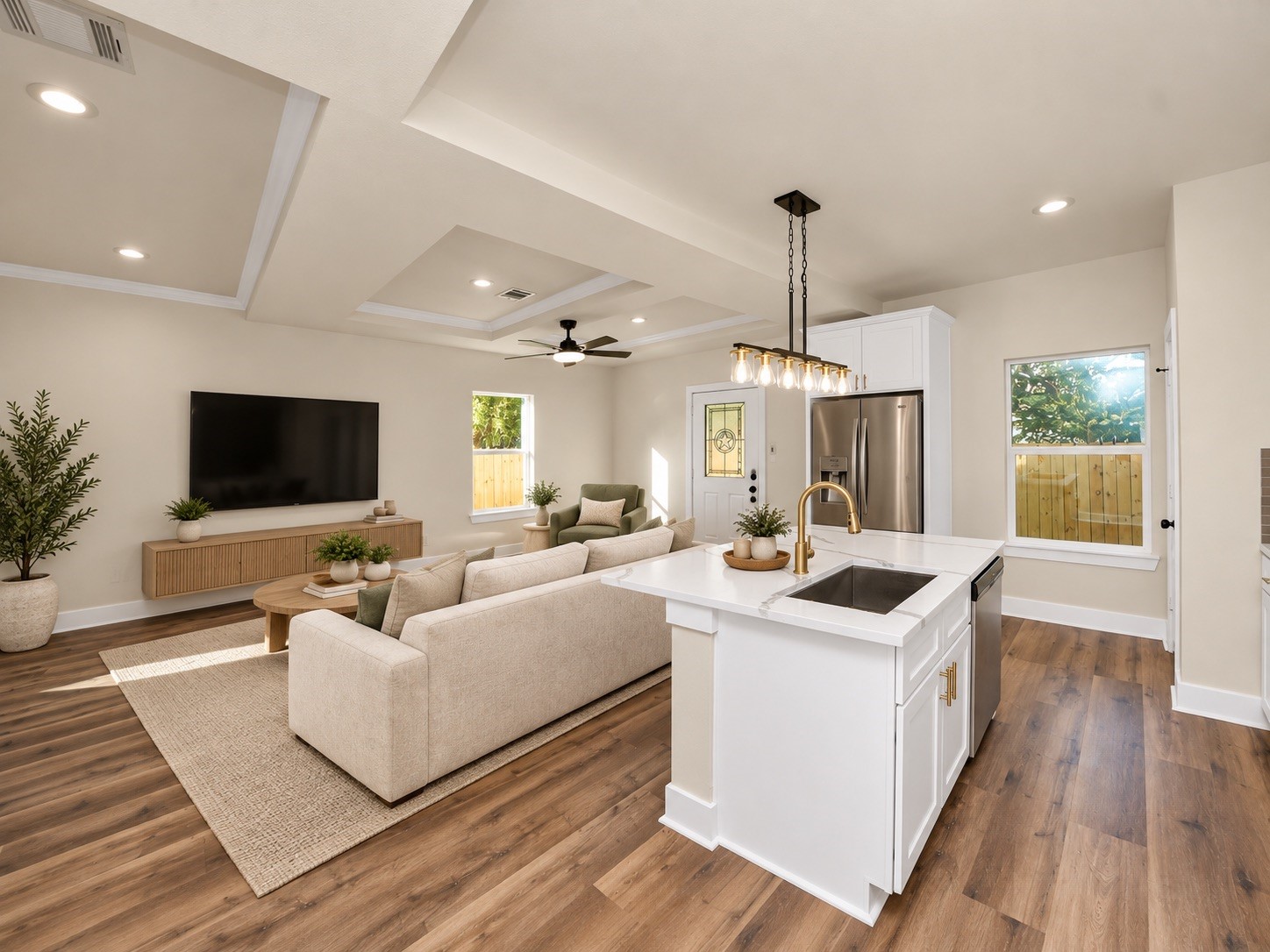 View from the kitchen showcasing the open-concept floor plan, oversized island, beautiful LVP flooring, decorative tray ceilings & abundant natural light | Virtually staged