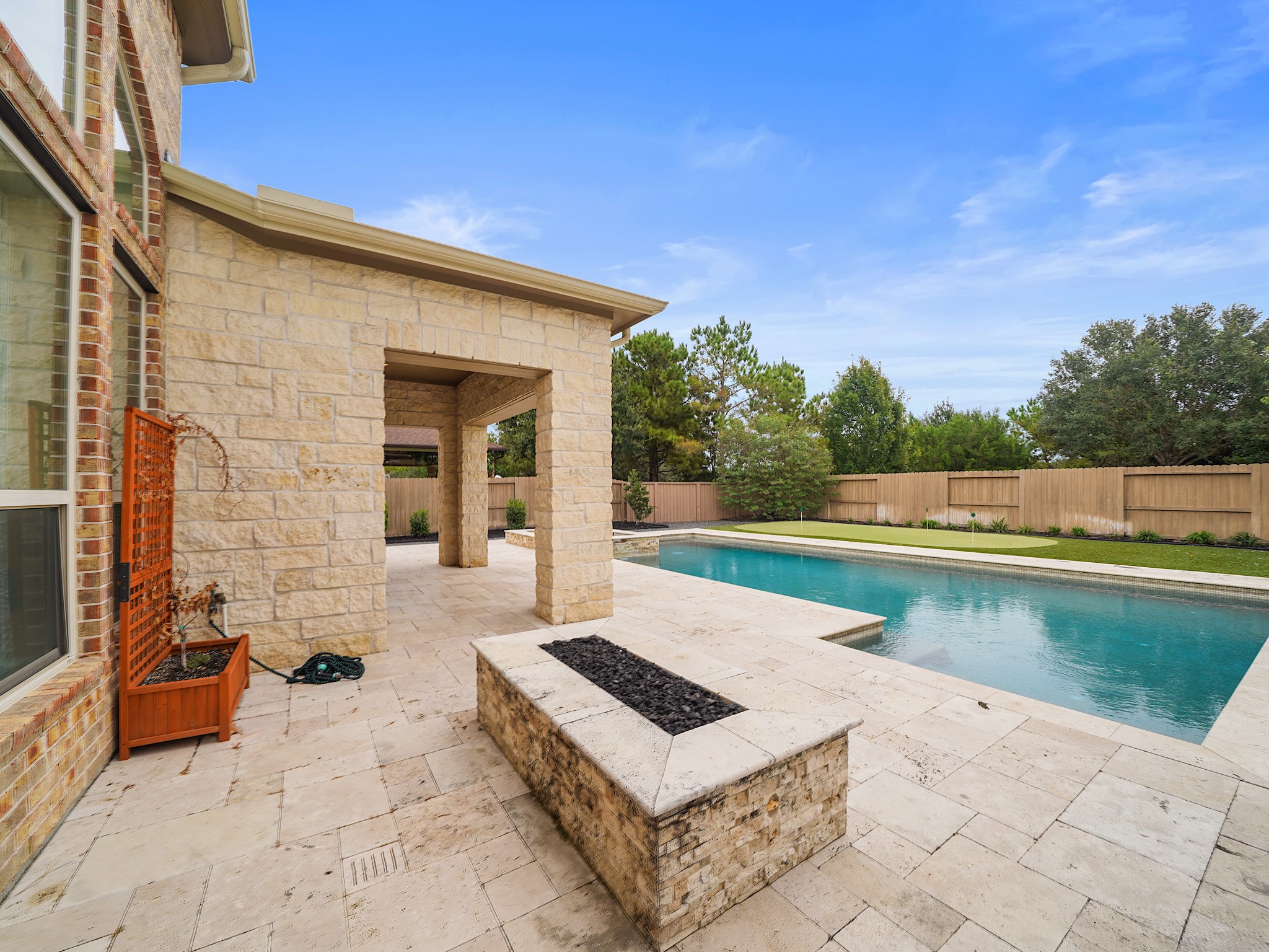As evening settles in, the firepit creates an inviting place to gather, extending the backyards resort-style atmosphere well beyond sunset.