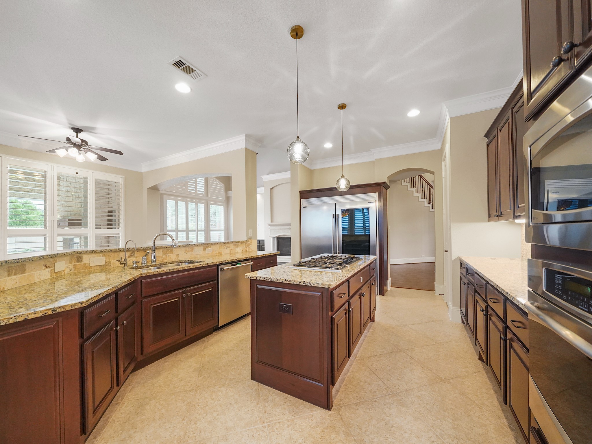 Rich cabinetry, granite counters, and a generous island with cooktop create a warm, functional kitchen that is as inviting for everyday meals as it is for entertaining.