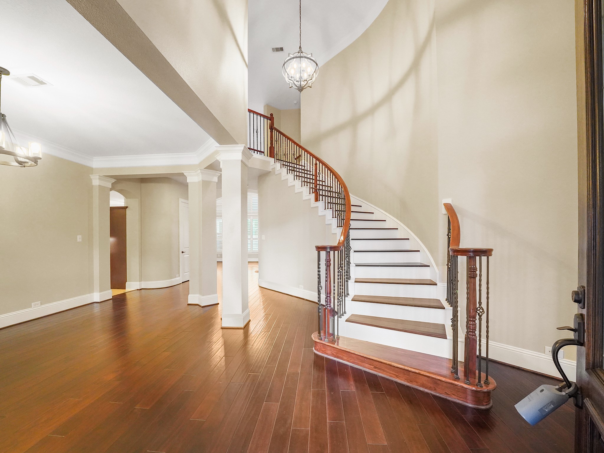 Inside, the grand foyer welcomes you with warm wood flooring, soaring ceilings, and a graceful curved staircasean elegant first look at the spaces beyond.