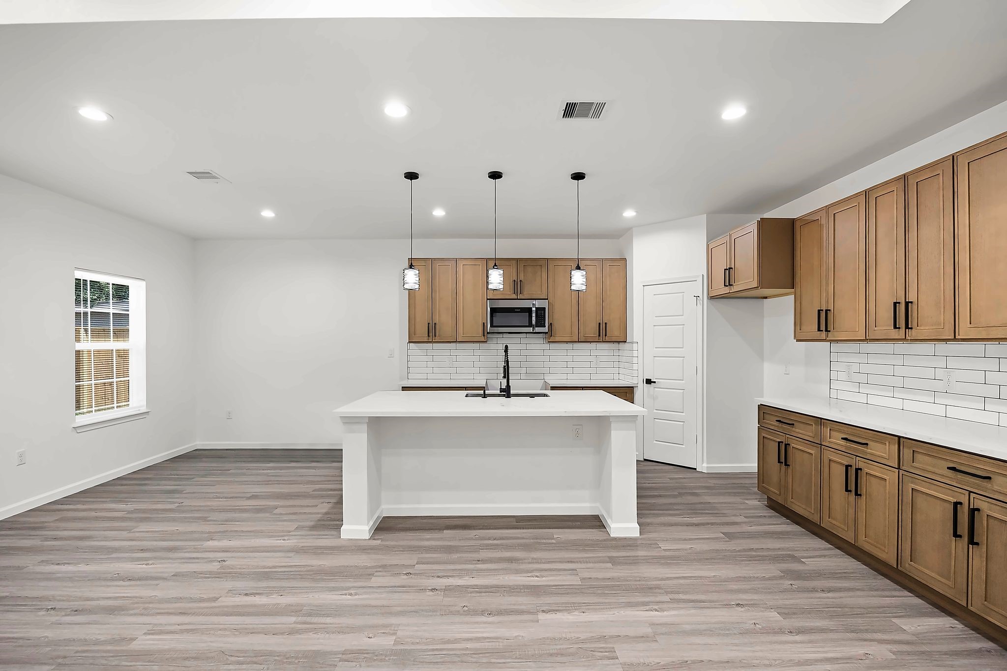 Modern kitchen with sleek cabinetry, a spacious island with pendant lighting, and stylish white subway tile backsplash.
